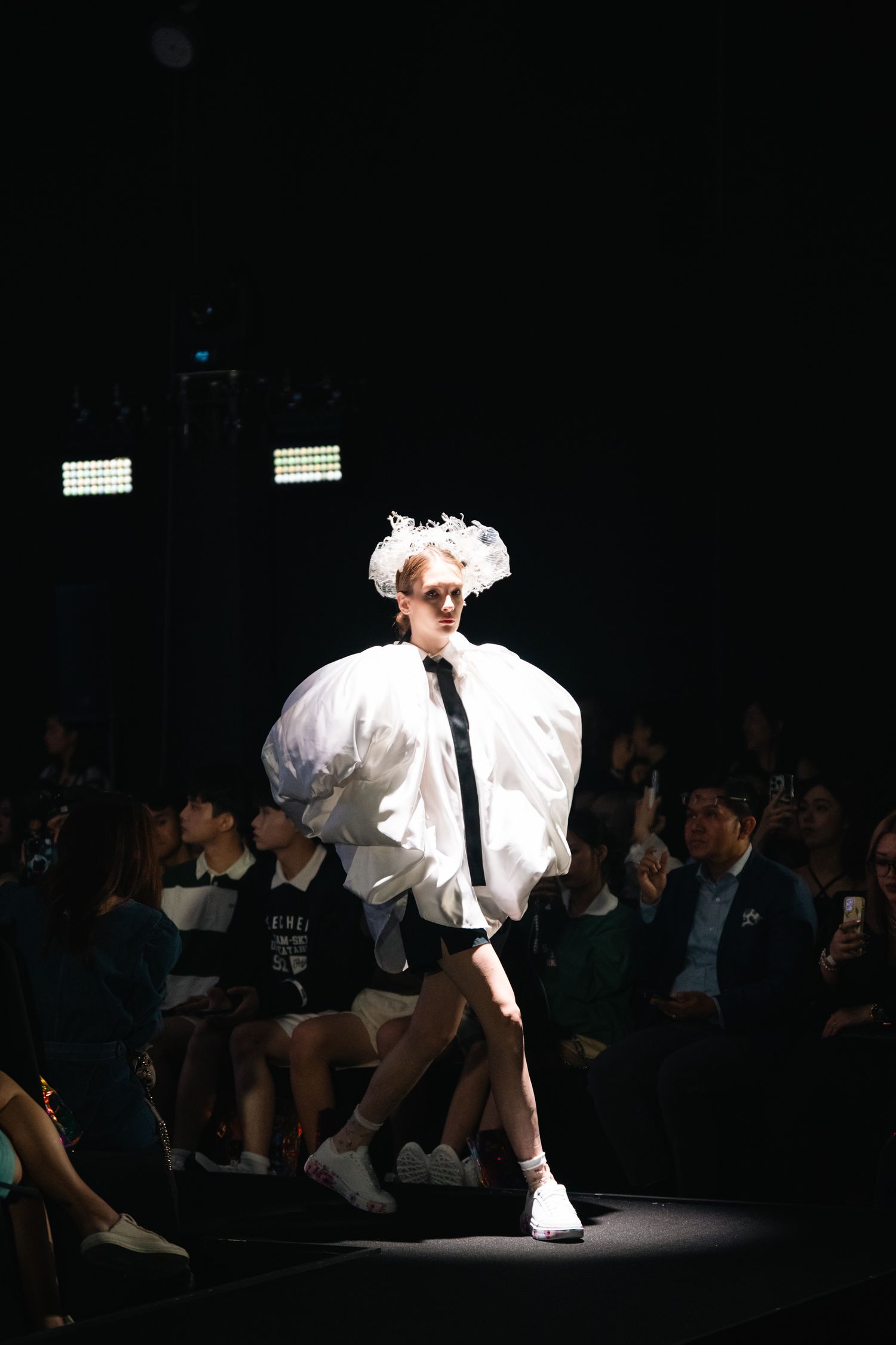 A dramatic silhouette of a model in a white puffy sleeve outfit walks the runway.