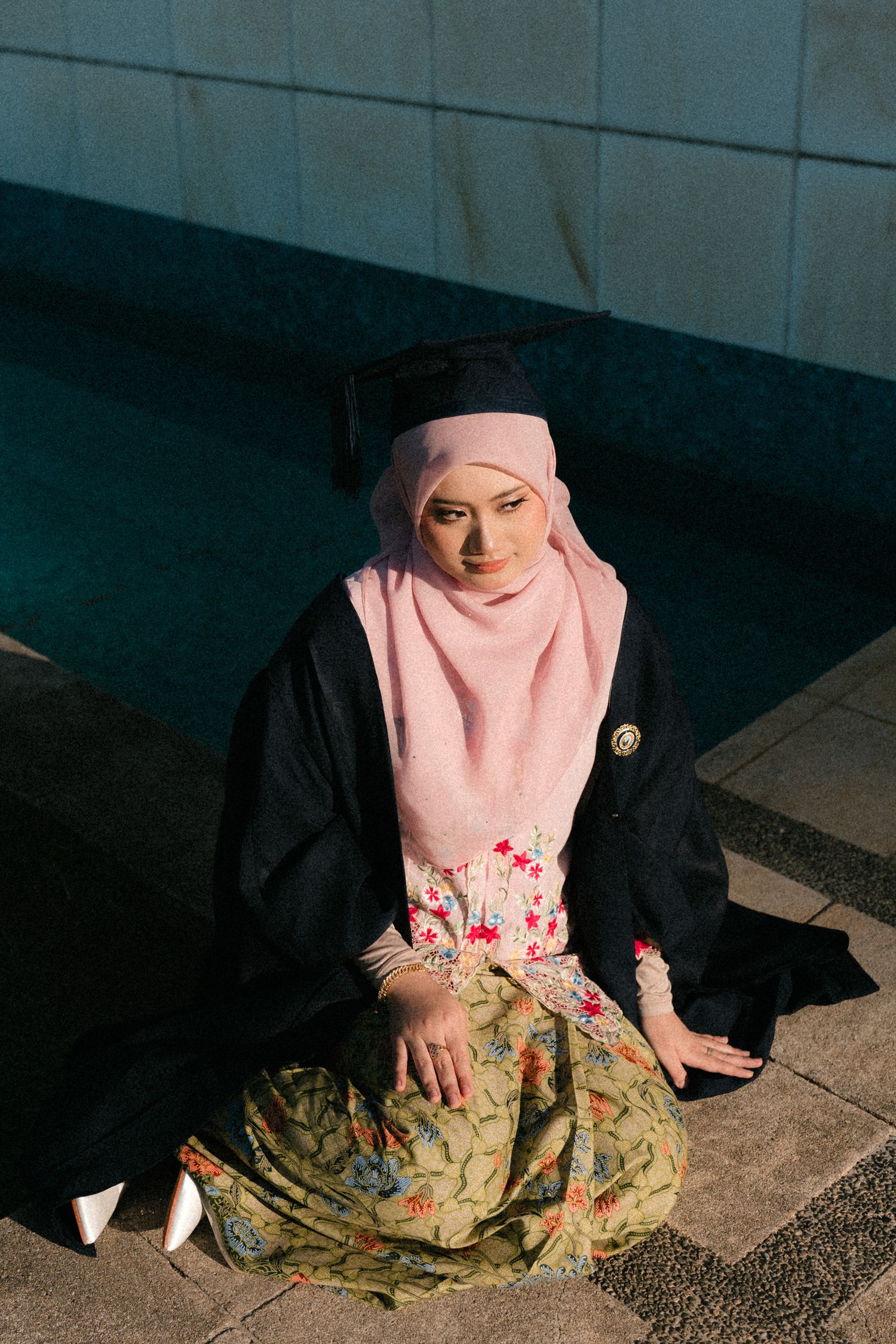 A sequence of photos showing someone in a pink hijab and floral skirt sitting on the ground.