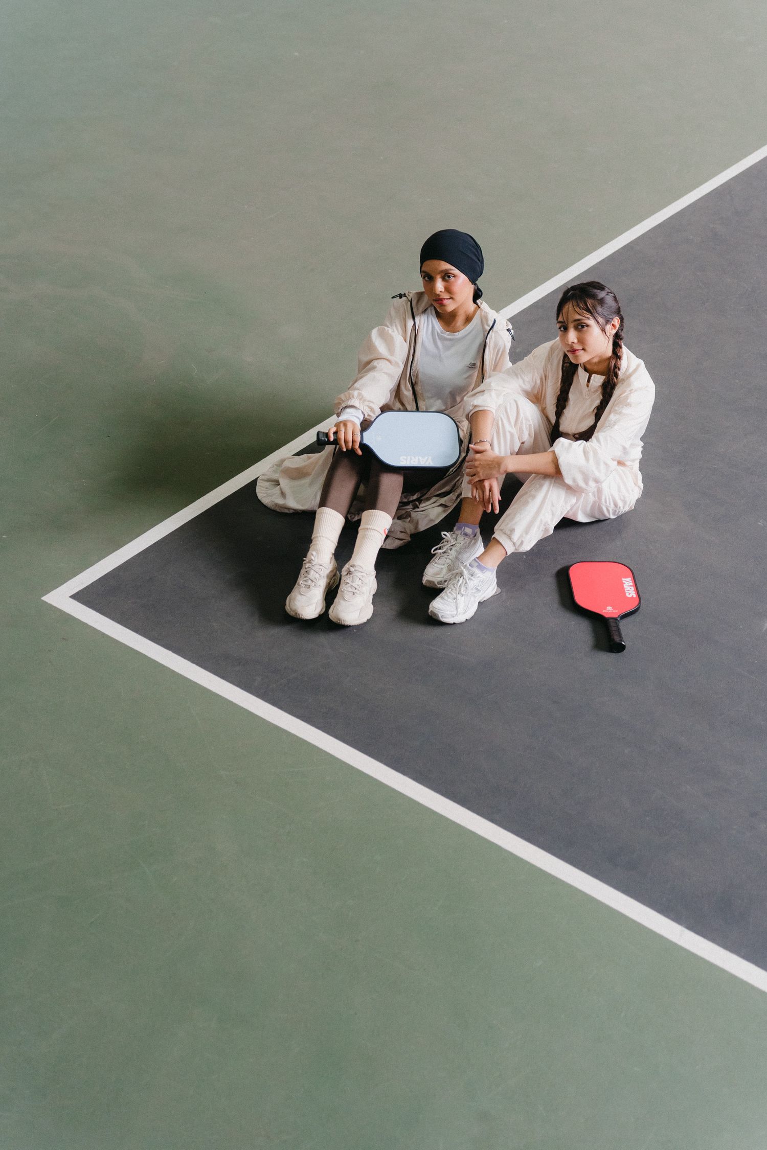 Two people in white sneakers sit together on a grey floor creating a series of minimalist composition photos.