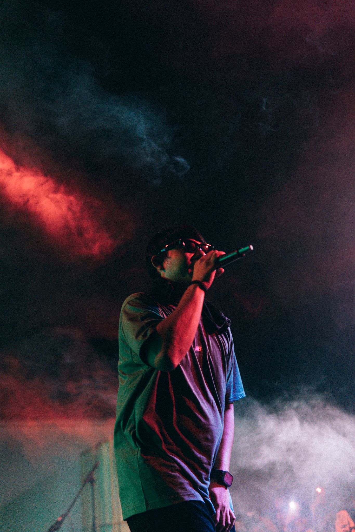 Concert performance with dramatic red and blue smoke effects on darkened stage.