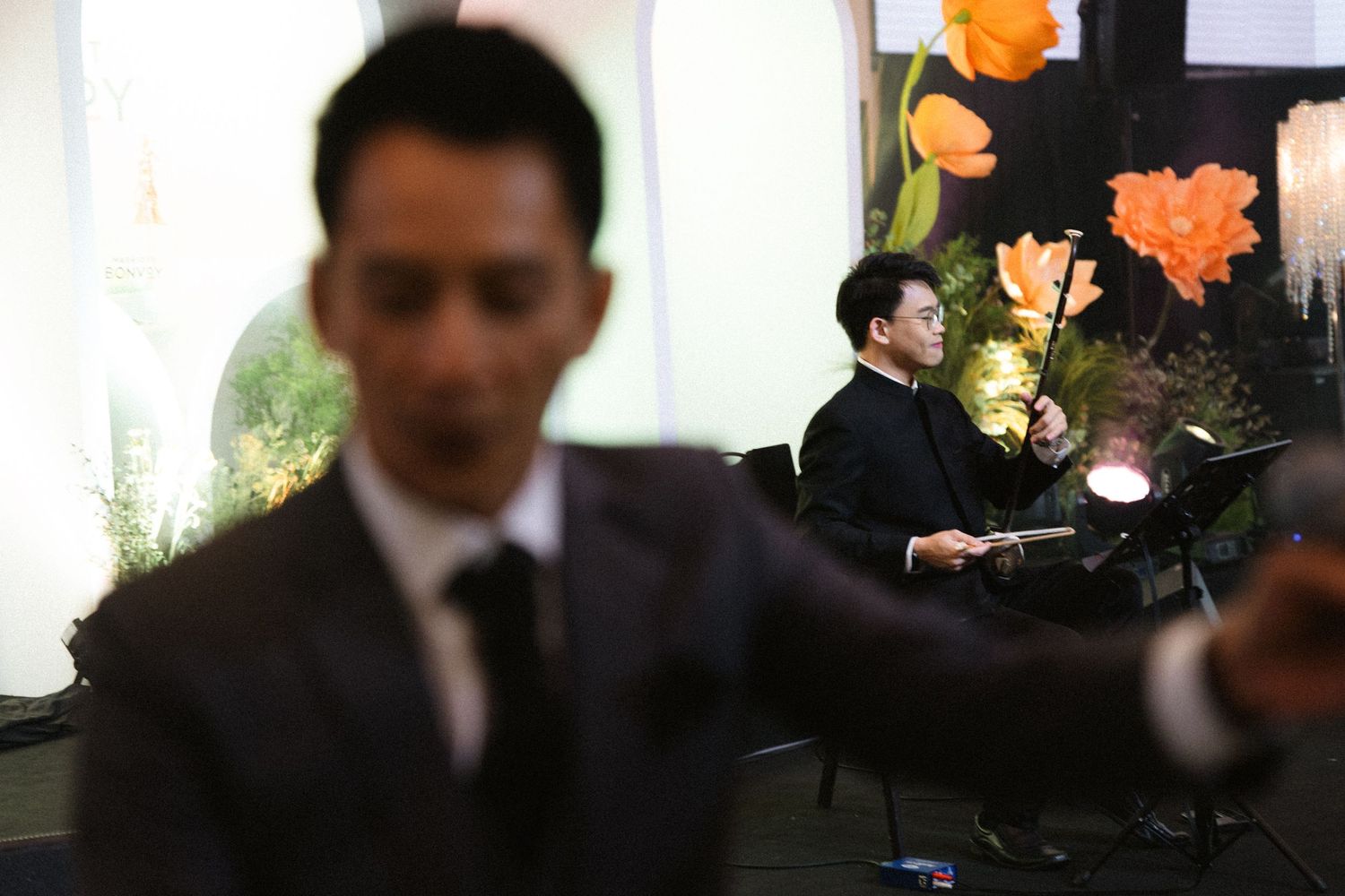 Blurred image of event staff with orange floral decorations in background.