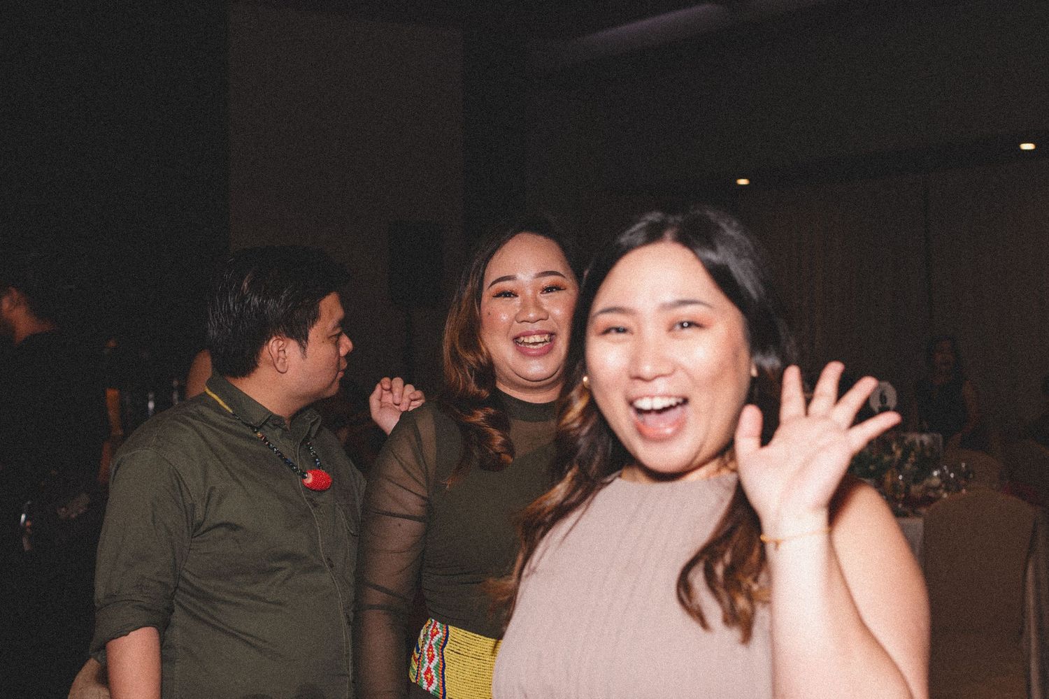 A group of friends enjoying themselves at a dimly lit party or social gathering.