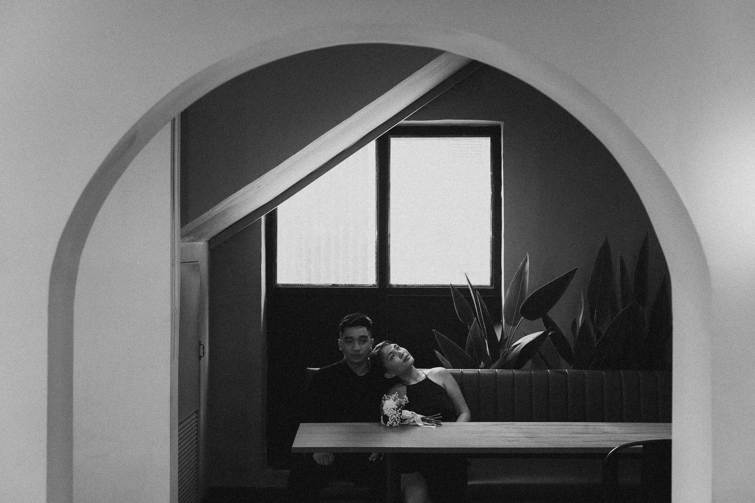 Artistic black and white composition of figures through arched doorway.