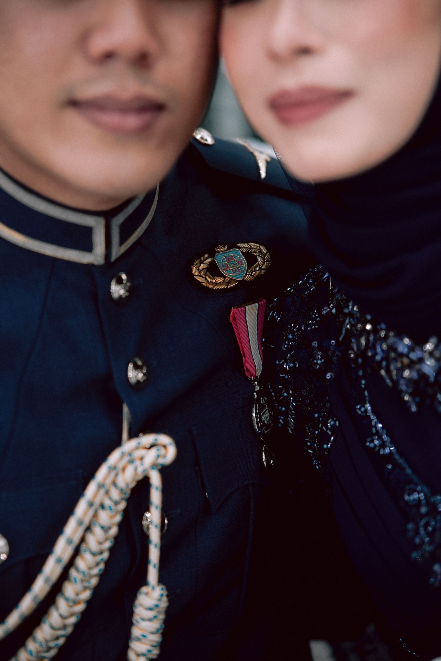 Close-up detail of military dress uniform with gold braided cords and medals against dark formal attire.