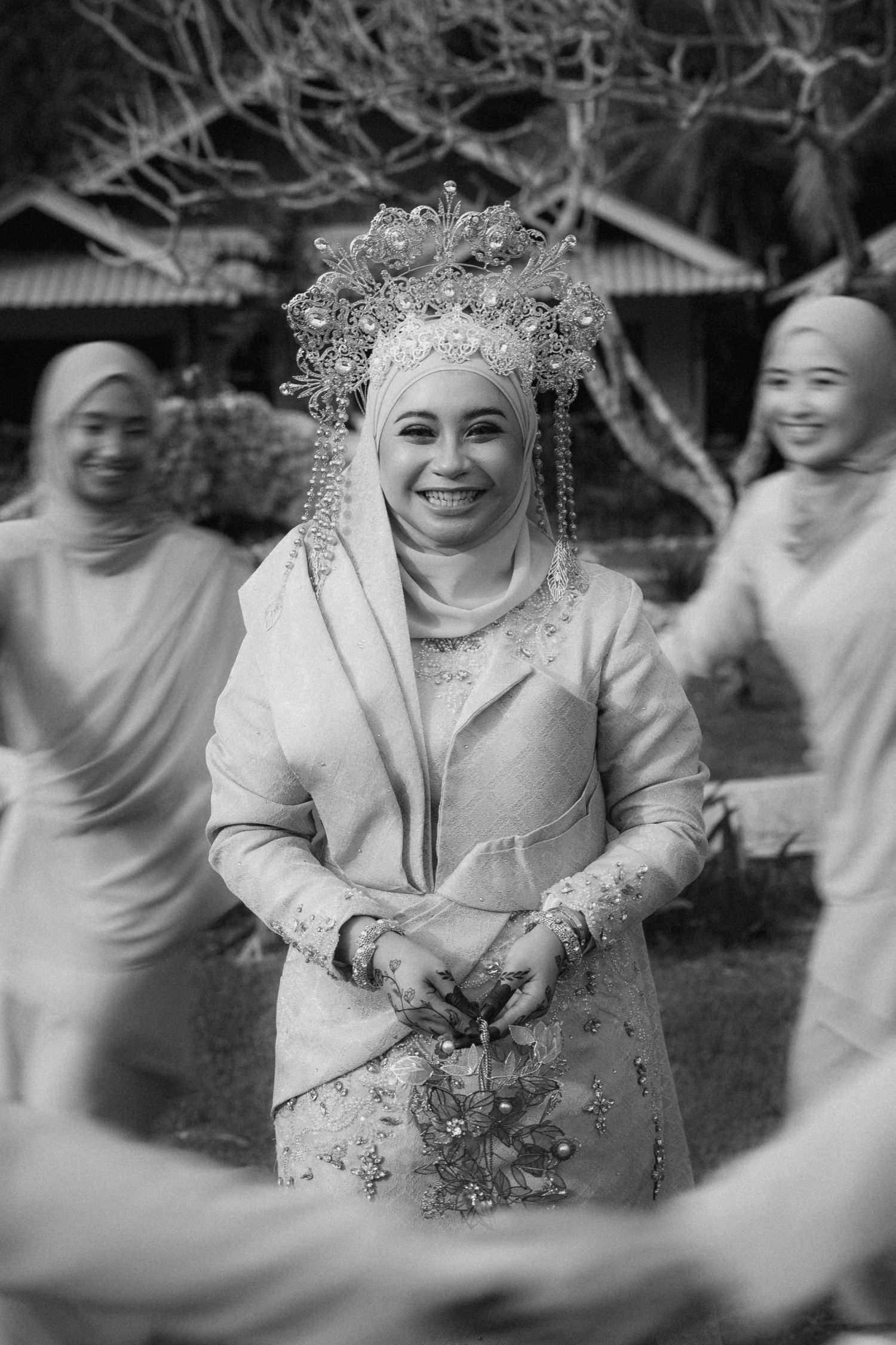 Black and white photo sequence of a bride in traditional wedding attire laughing and dancing during a celebration outdoors.