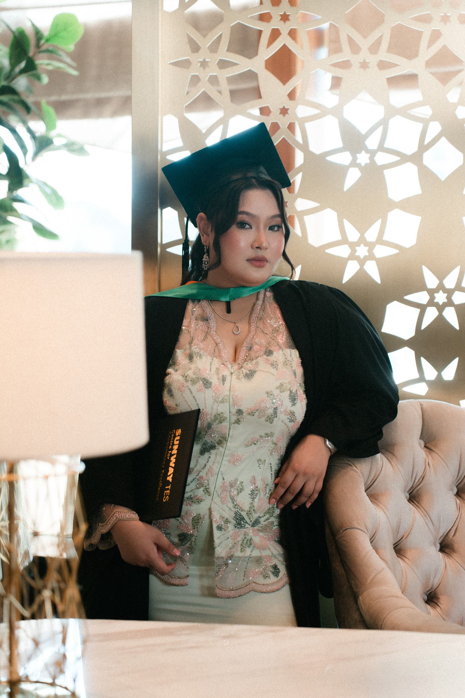 A floral dress is showcased against a decorative wall with geometric cutout patterns in an elegant interior setting.