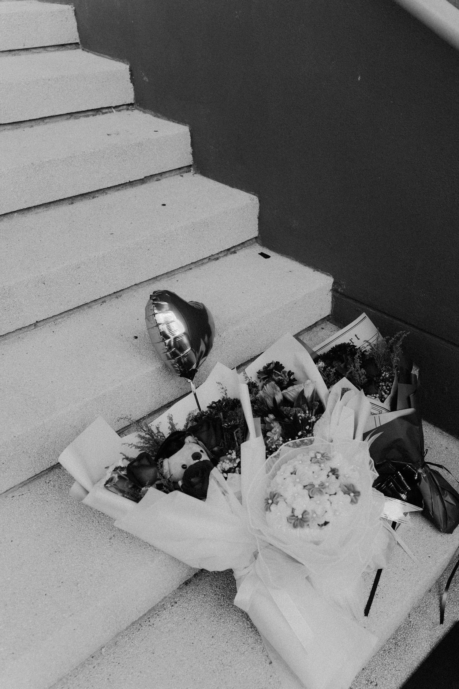 A black and white photo sequence shows a bouquet of flowers falling down concrete steps.