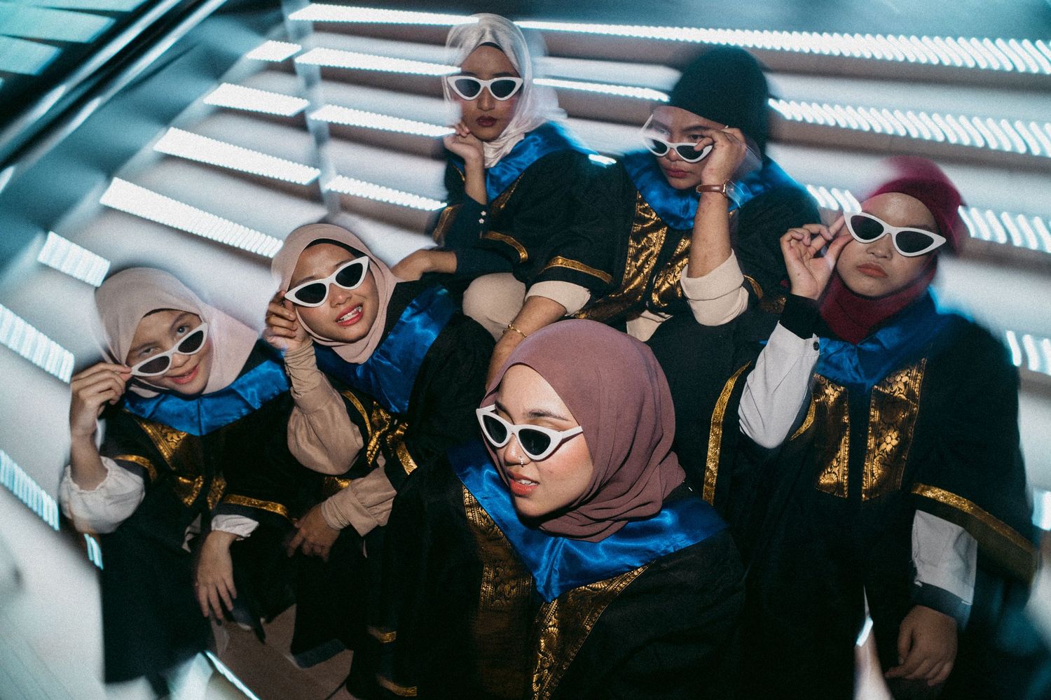 A group wearing white sunglasses and casual attire poses together on stairs.