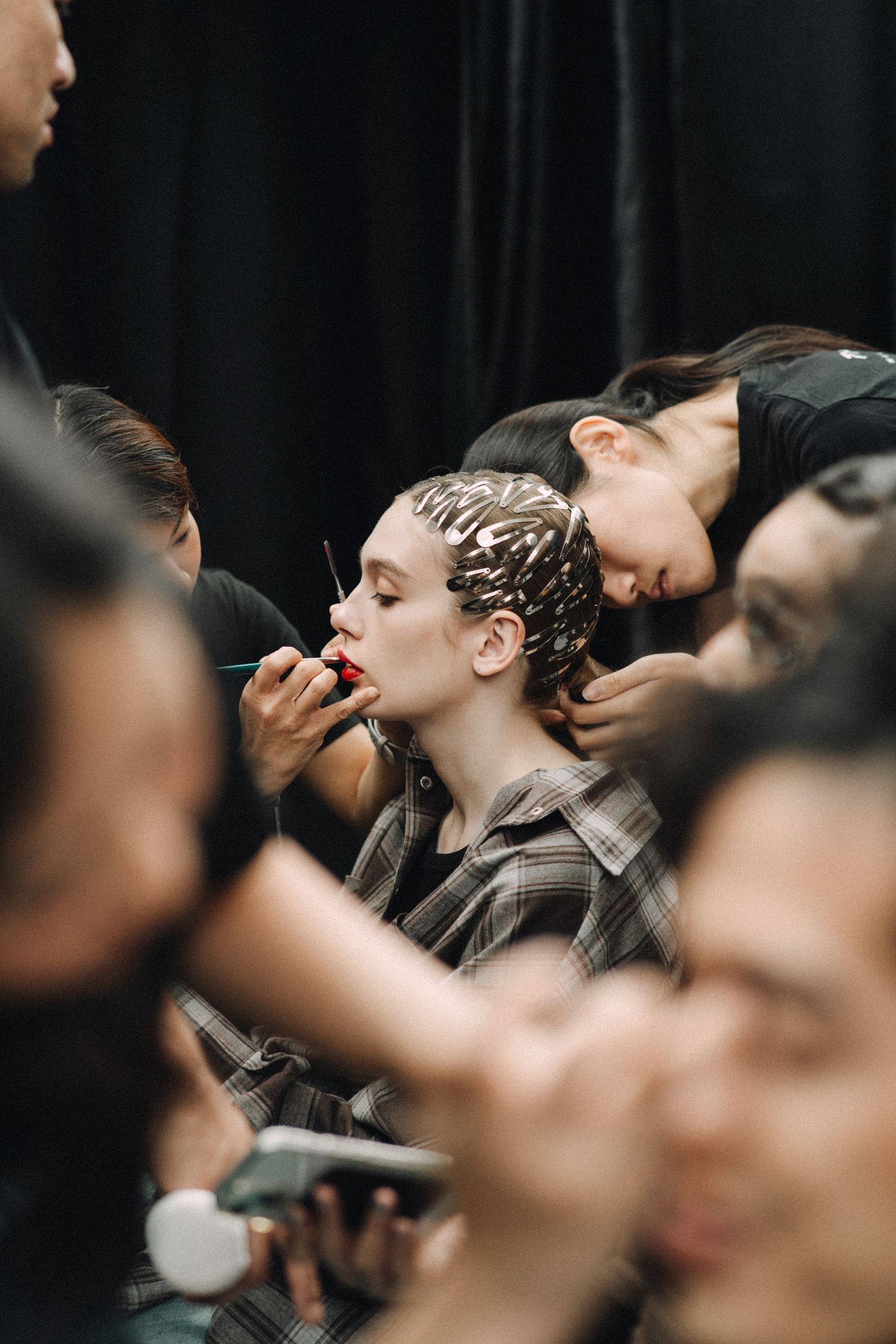 Behind the scenes makeup artist applies cosmetics to model before fashion show.