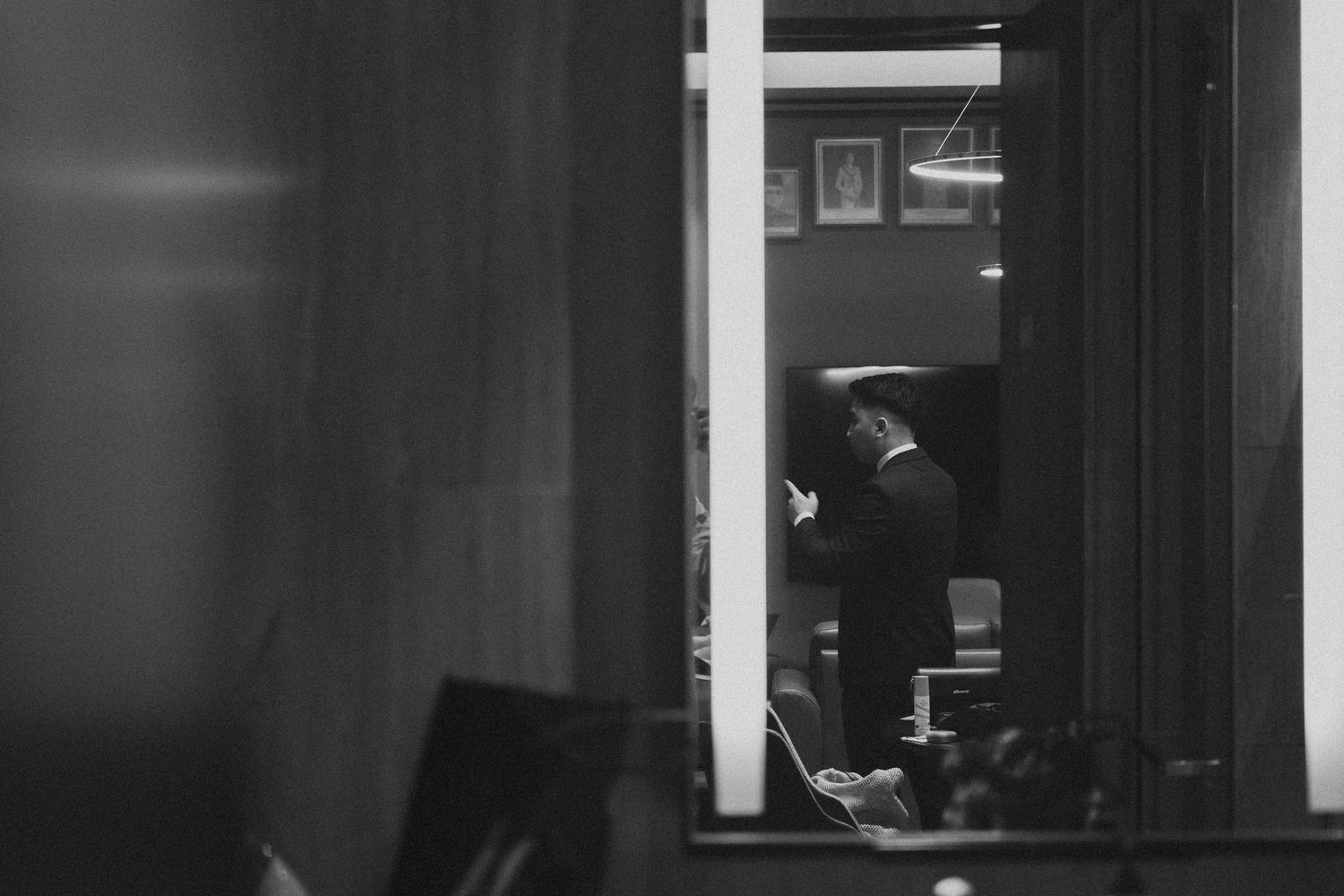 Through a window opening, a silhouette examines papers in dimly lit office space at night.