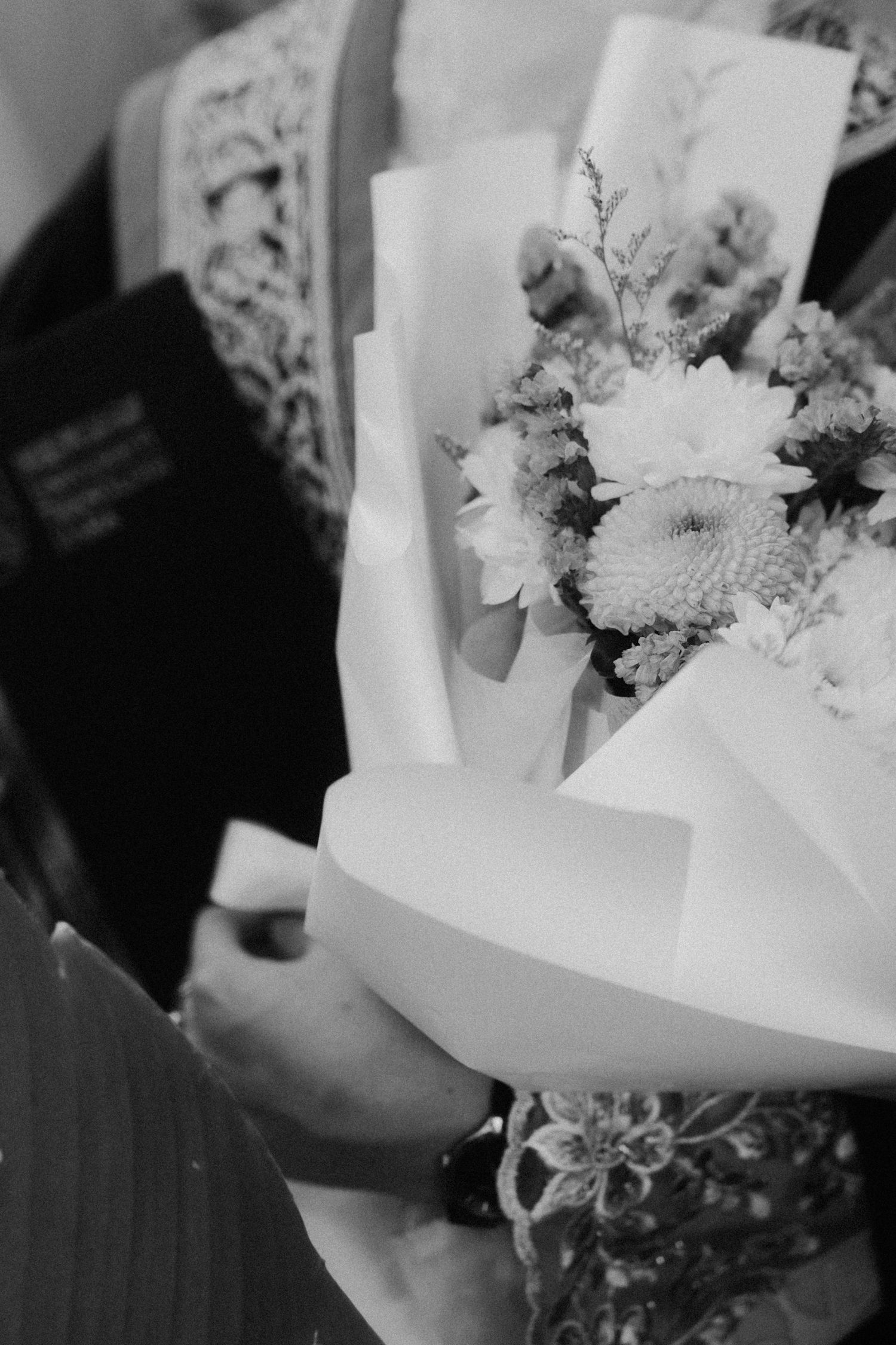 Black and white images showing a person holding a wrapped bouquet of white flowers and delicate foliage.
