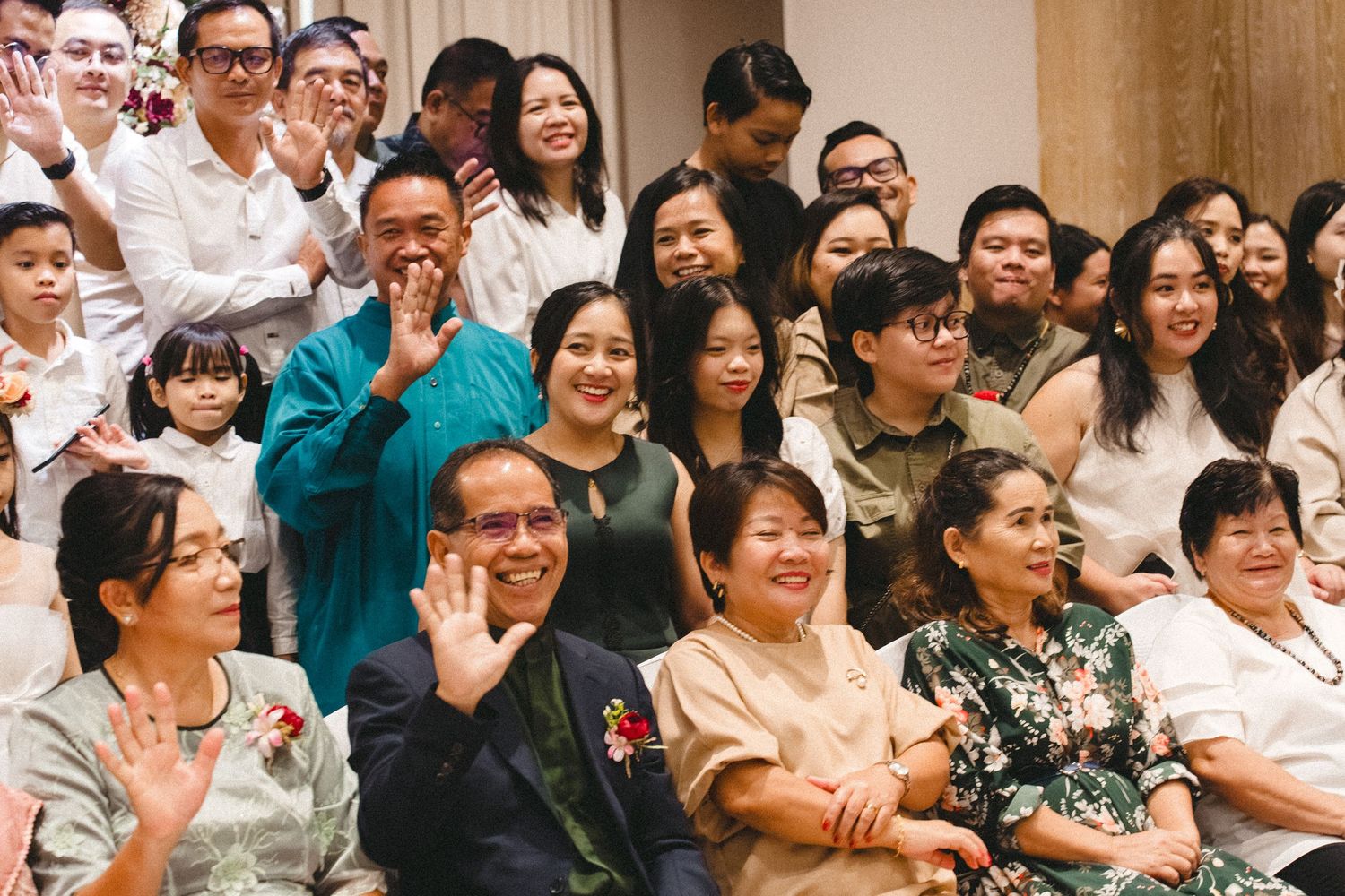 A crowd of audience members react with enthusiasm and smiles during an indoor event.