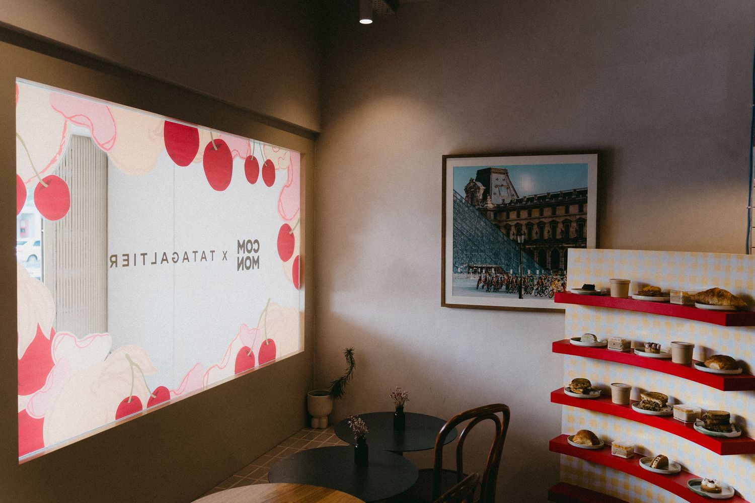 Modern cafe interior with red decorative lighting and wall display shelves.