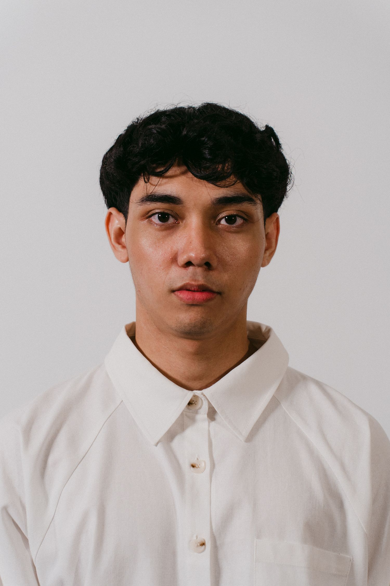 Portrait of person in crisp white button-down shirt against neutral background.
