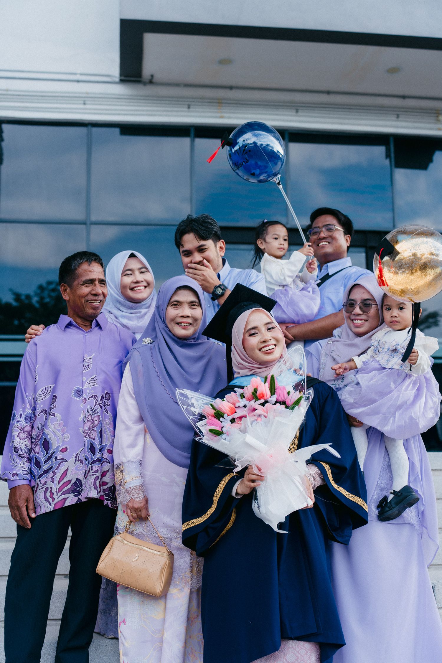 A group of people wearing coordinated purple and white outfits pose together for a celebratory photo.