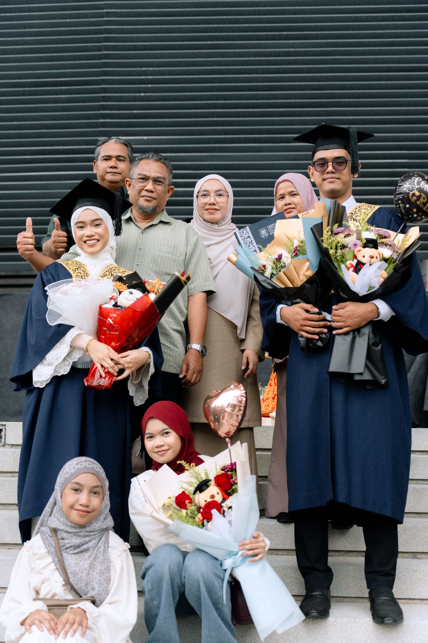 A group of people in formal attire holding colorful flower bouquets stand together in a row.