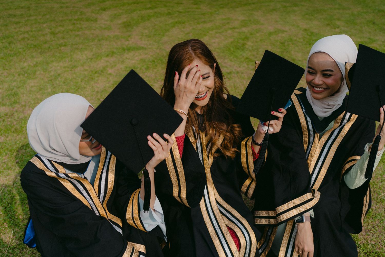 Graduates in black and gold graduation robes share an emotional moment during their celebration.