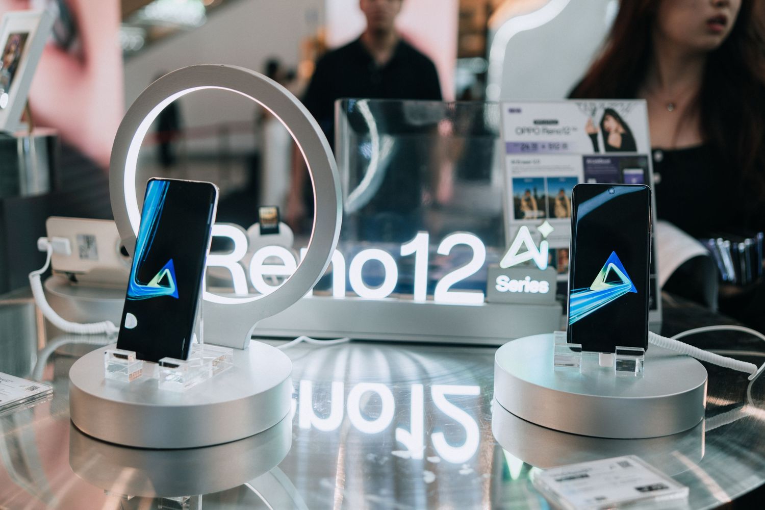 Two mobile phones displayed on white circular stands with blue illuminated screens in a retail environment.
