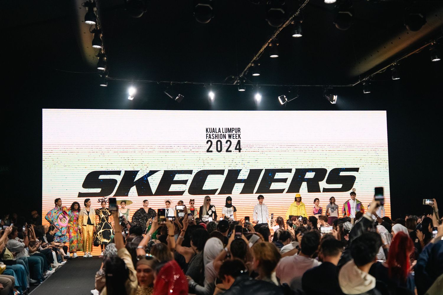 A crowded fashion show audience watches the Skechers 2024 runway presentation.