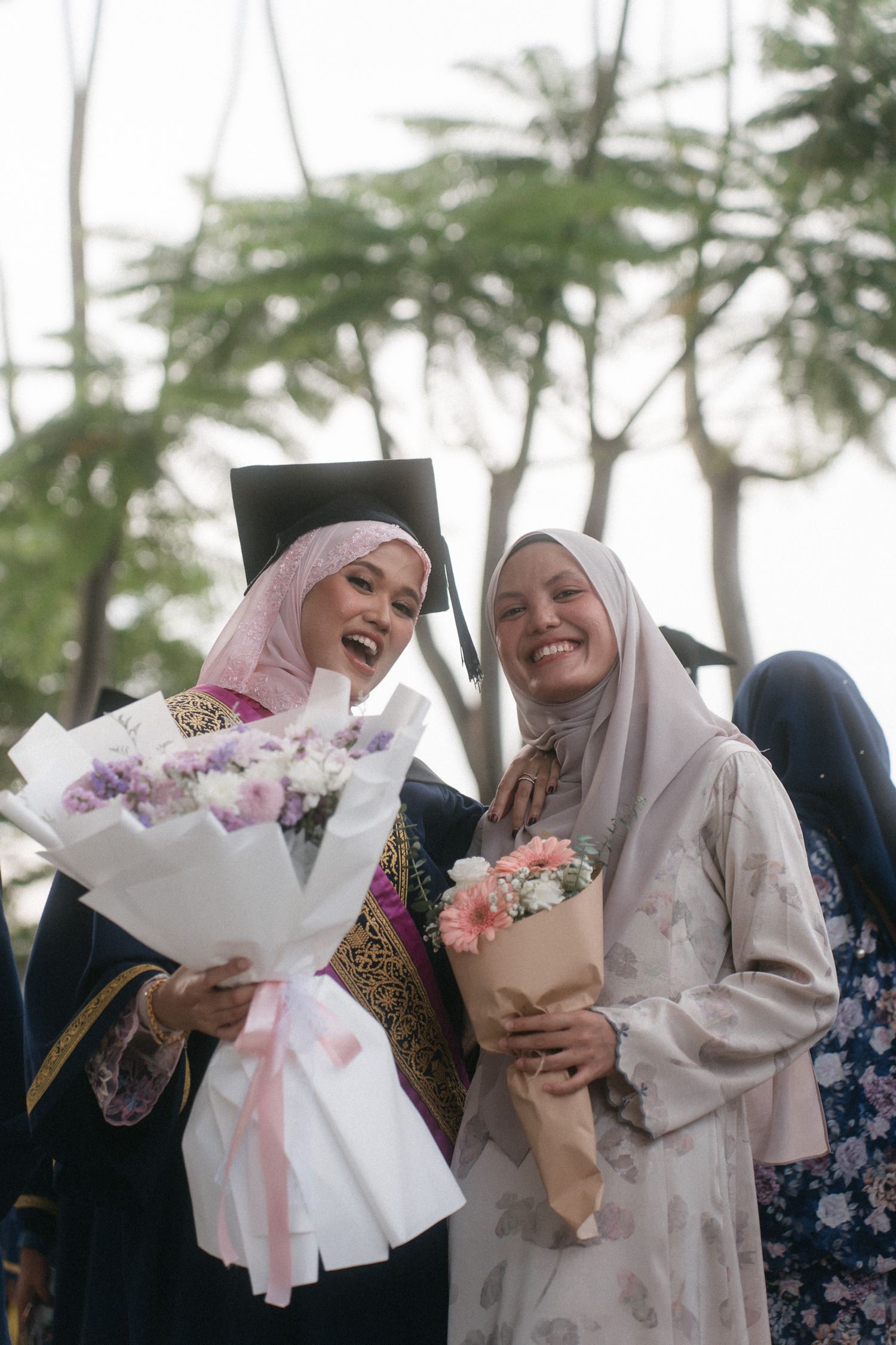 A group shares joyful moments while holding beautiful flower bouquets in an outdoor setting with palm trees.