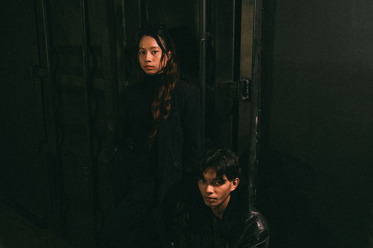 Two figures posing dramatically in a dark hallway or corridor.