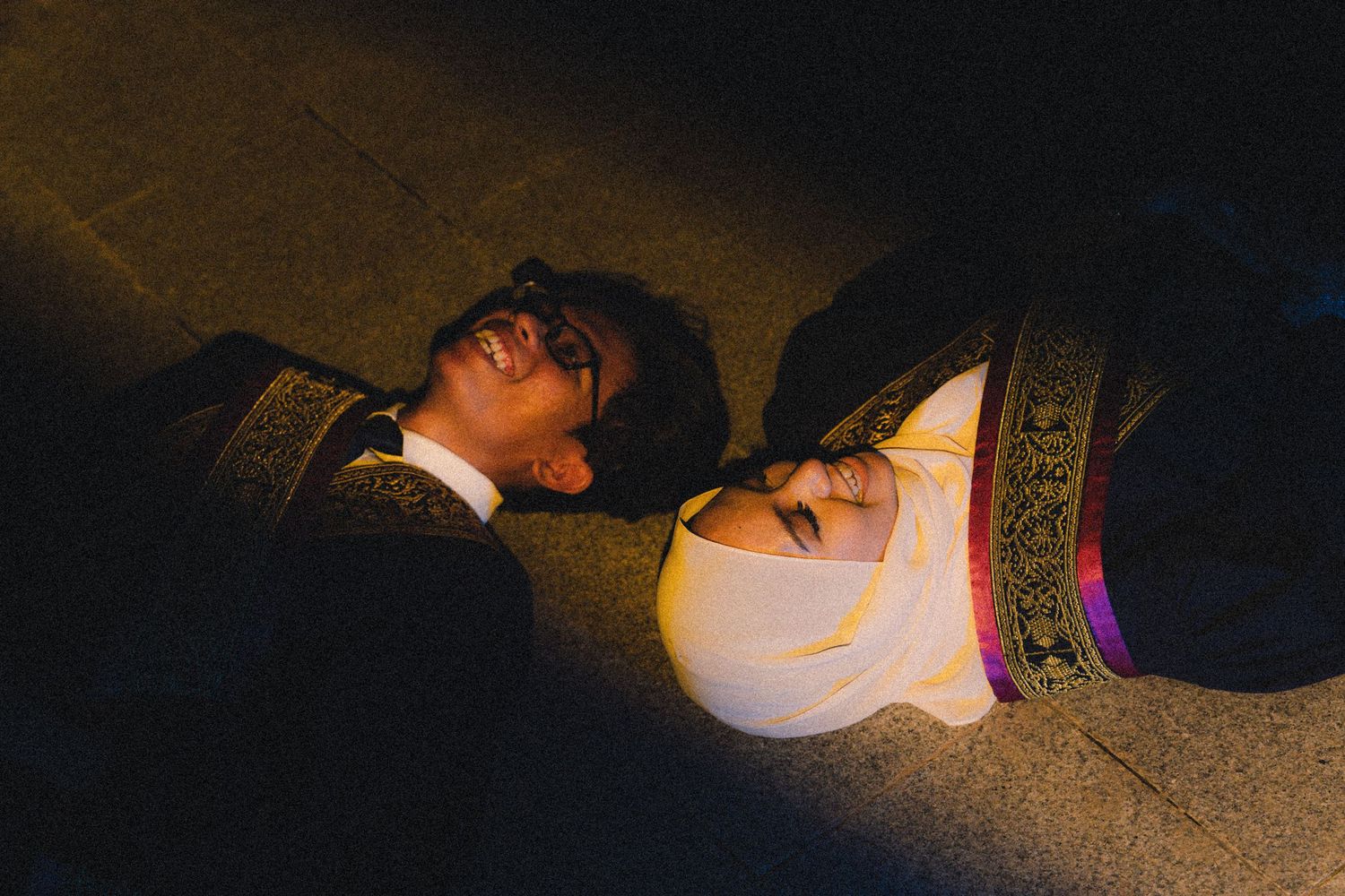 Two figures lay close together in dramatic low-key lighting.