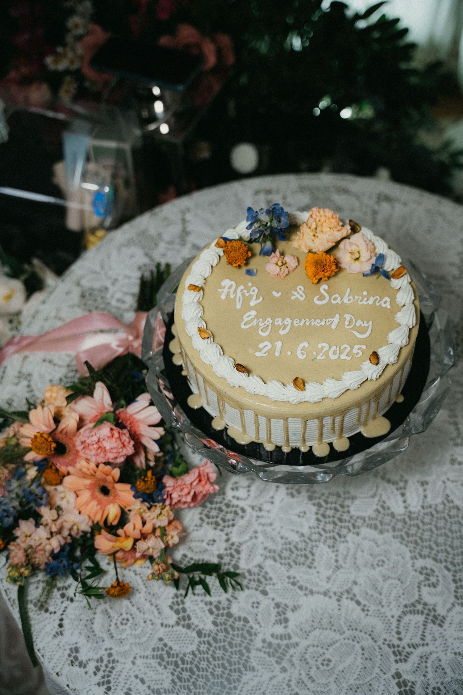 Decorative dessert cookies with gold lettering and flowers arranged on a white lace tablecloth.