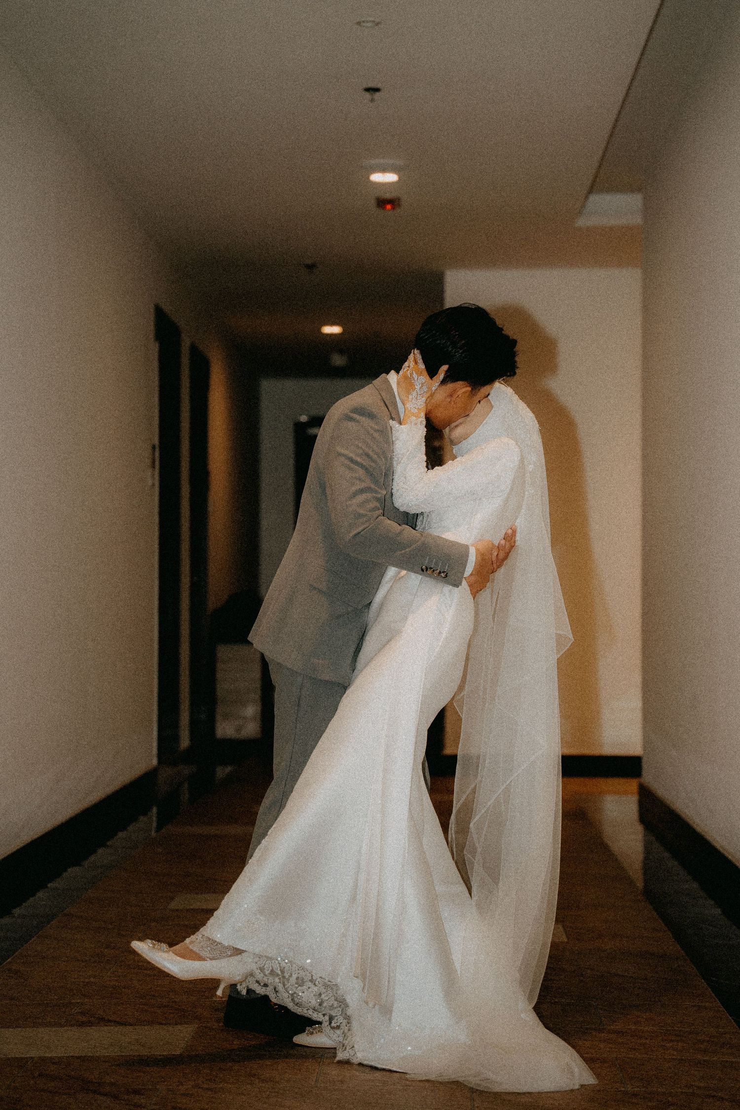 A series of five connected photos showing graceful movement of a white wedding dress and veil in a dimly lit hotel hallway.