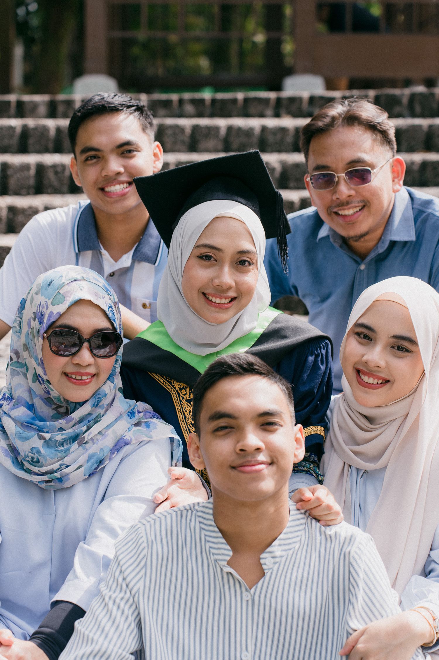 A group of students wearing white hijabs and light blue attire smiling together outdoors.