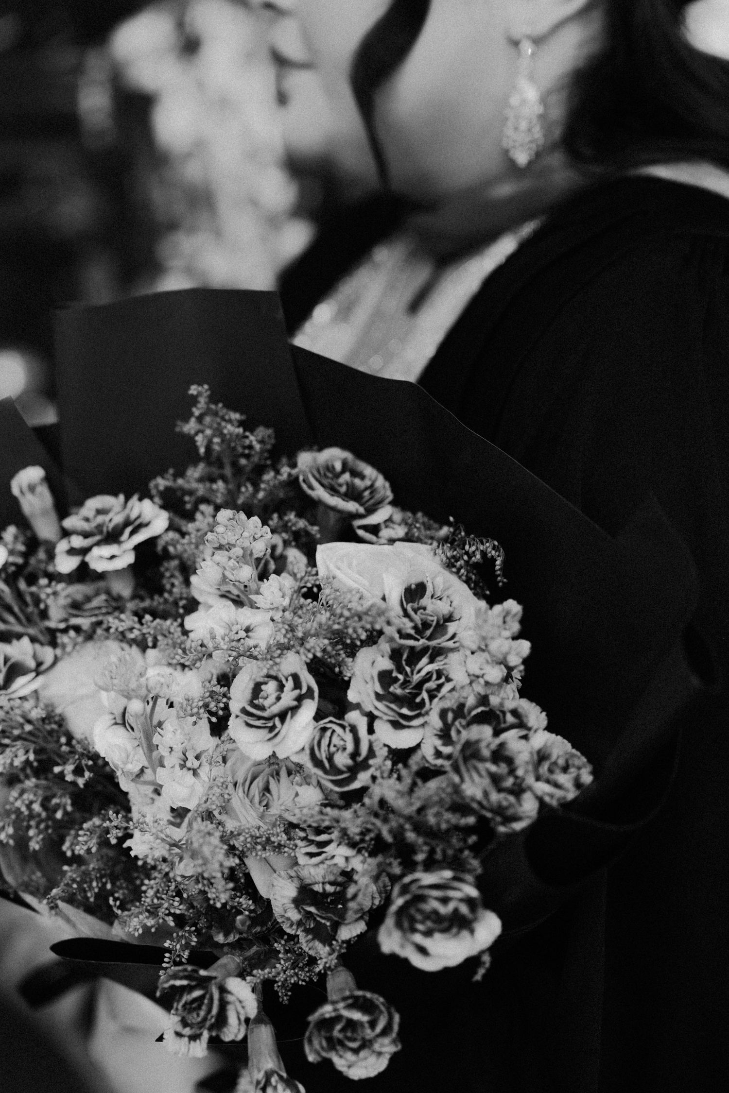 Black and white photo of elegant wedding bouquets with roses and mixed flowers arranged in a row.