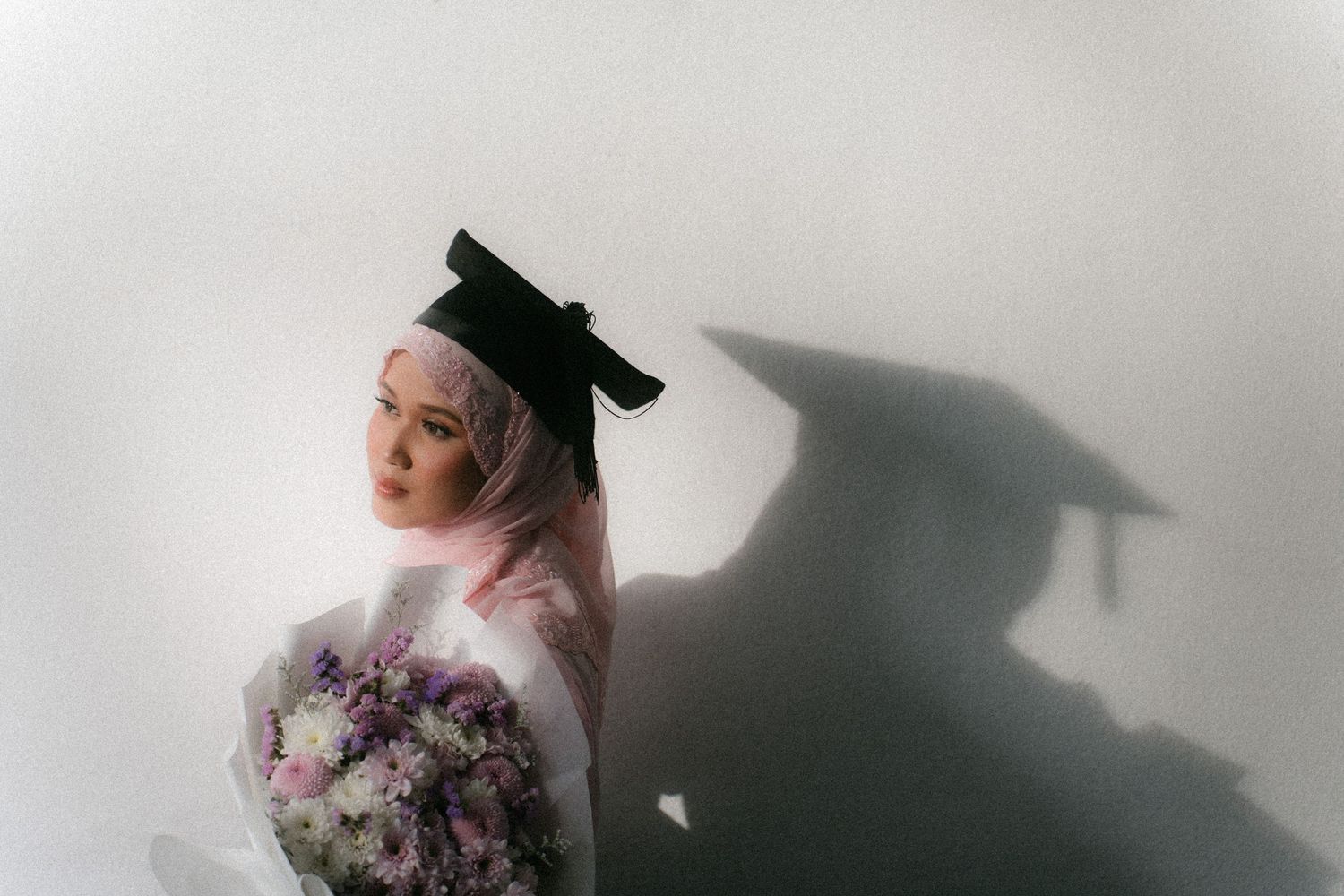 A person in black and white poses with flowers against a light background creating a dramatic artistic portrait.