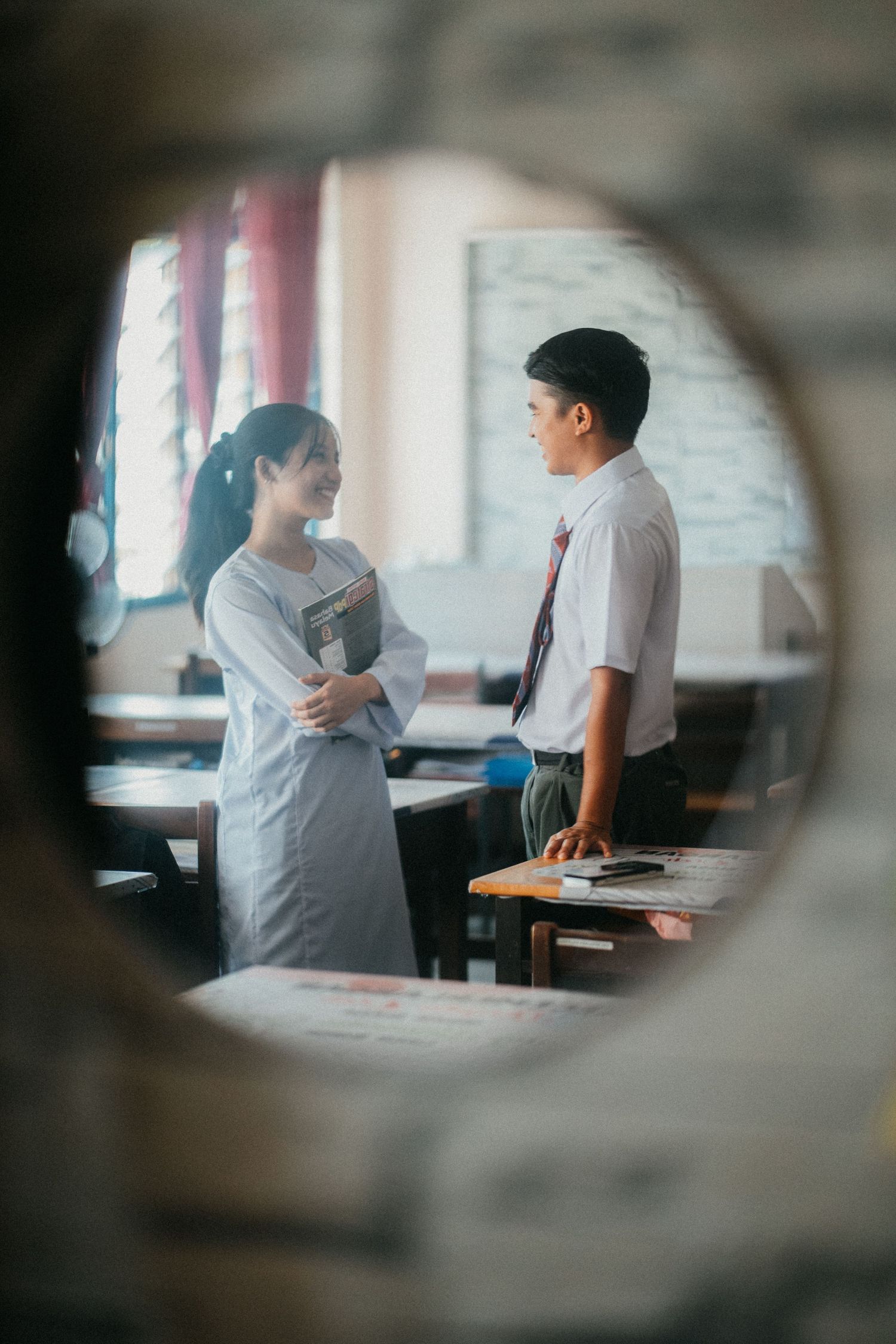 Two people having an animated discussion in an office setting through blurred circular frames.