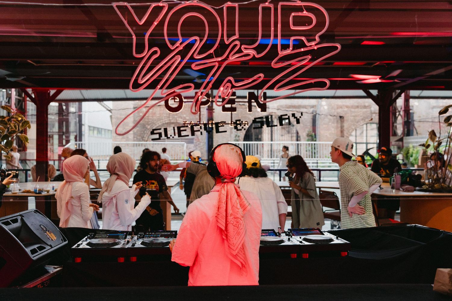 A neon sign reading 'YOUR' glows in red against a dark background with a reflective surface.
