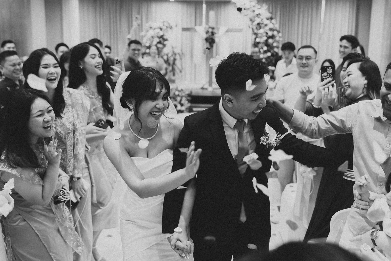 Black and white photo of wedding celebration with guests throwing confetti at dancing newlyweds.