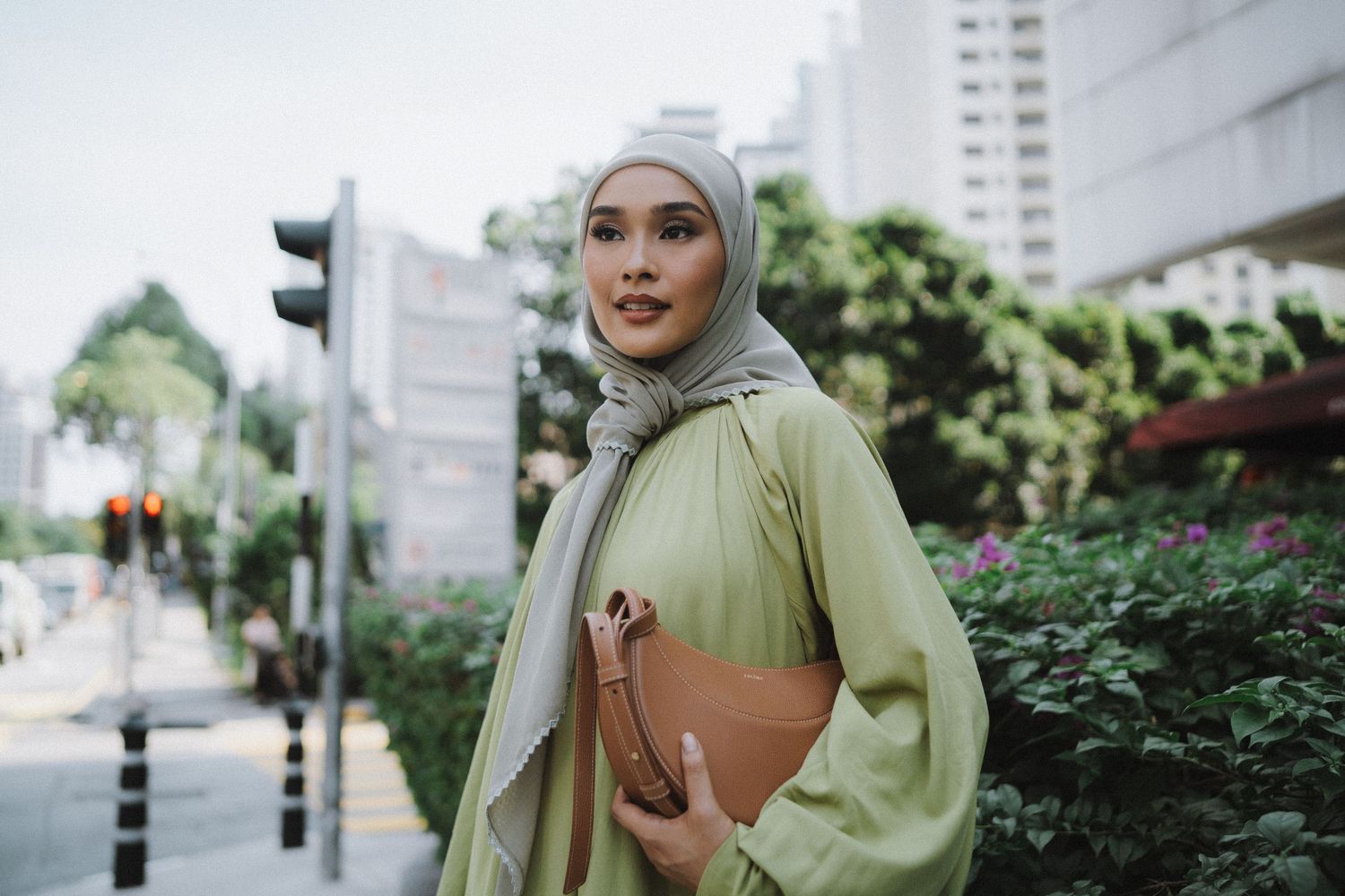 Street style photo of person in mint green outfit carrying brown clutch in urban setting.