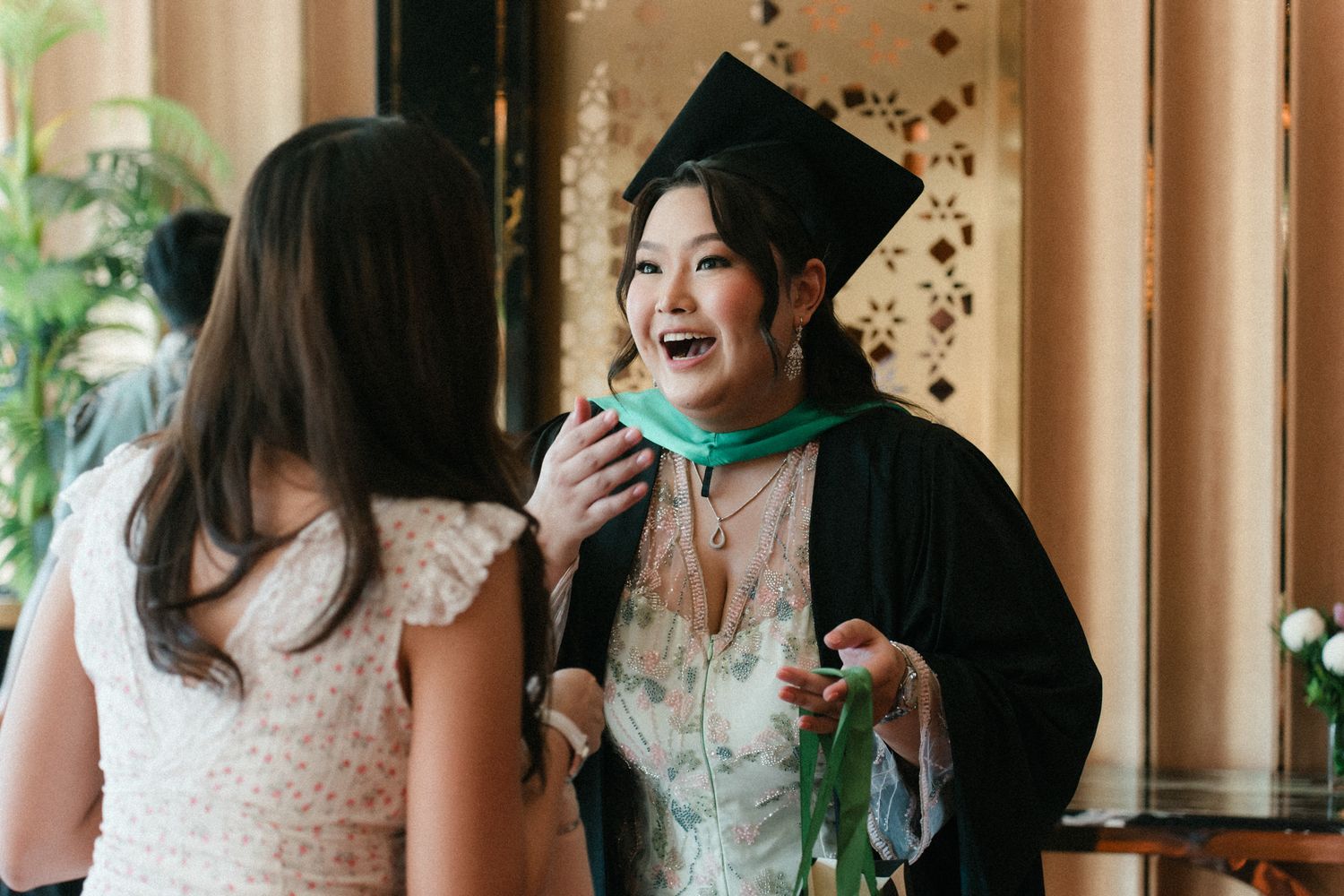 A group of wedding guests in formal attire share joyful laughter and conversation during a celebration.