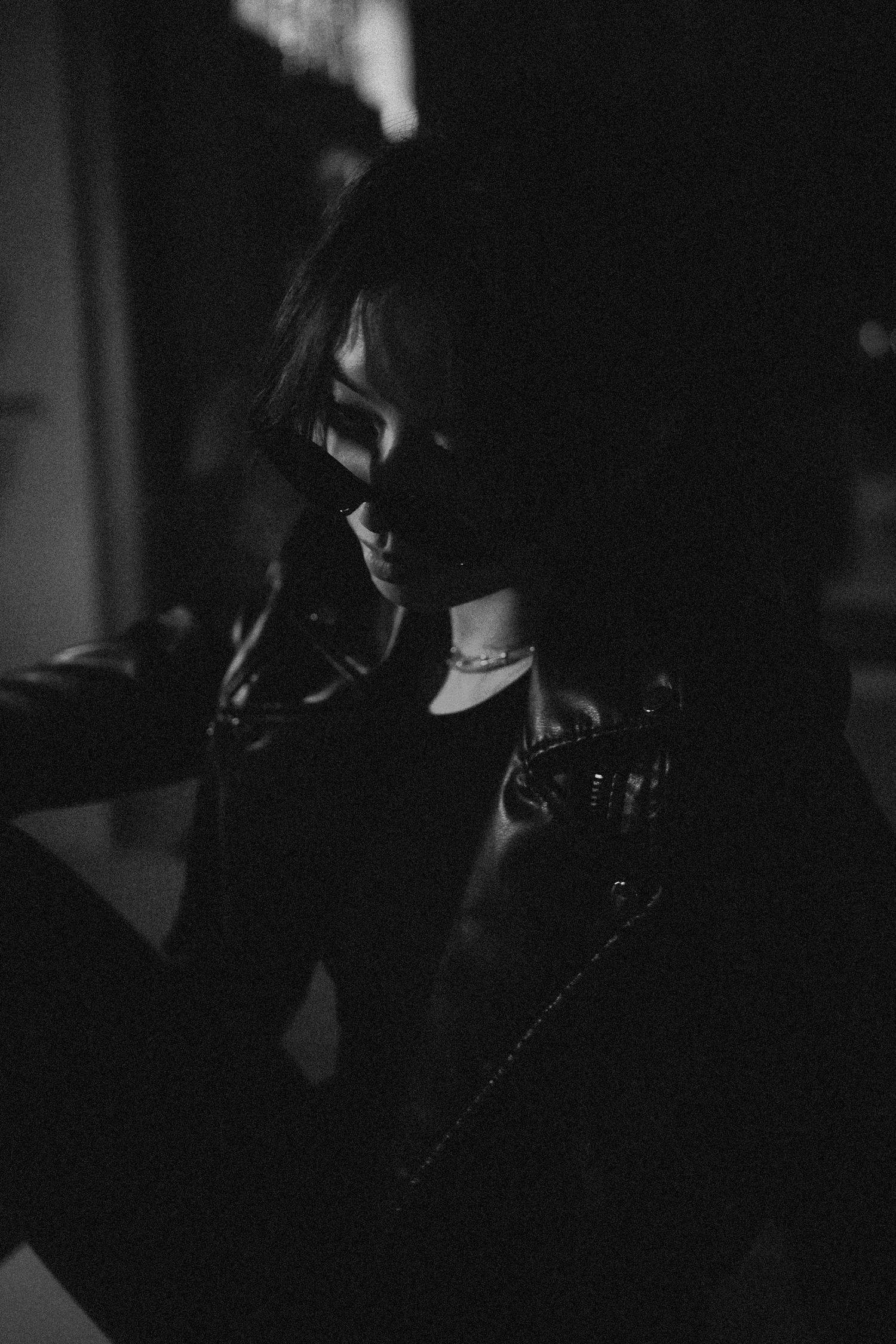 Moody low-light portrait showing figure in dark clothing and dramatic shadows.