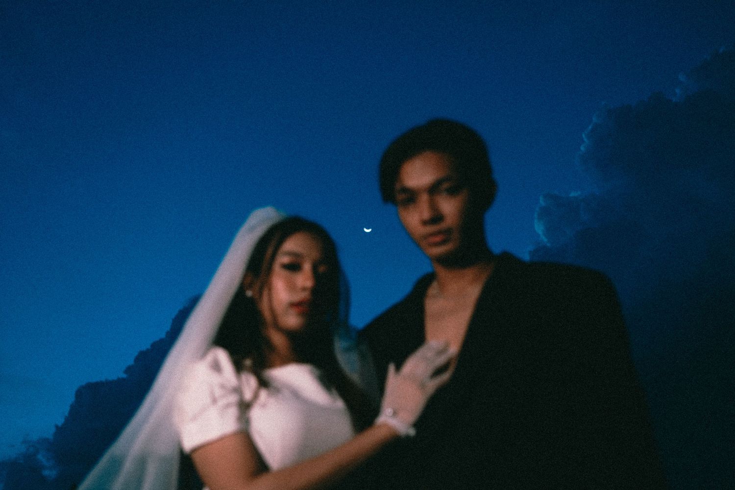 Moody twilight portrait of couple in wedding dress and dark clothing.