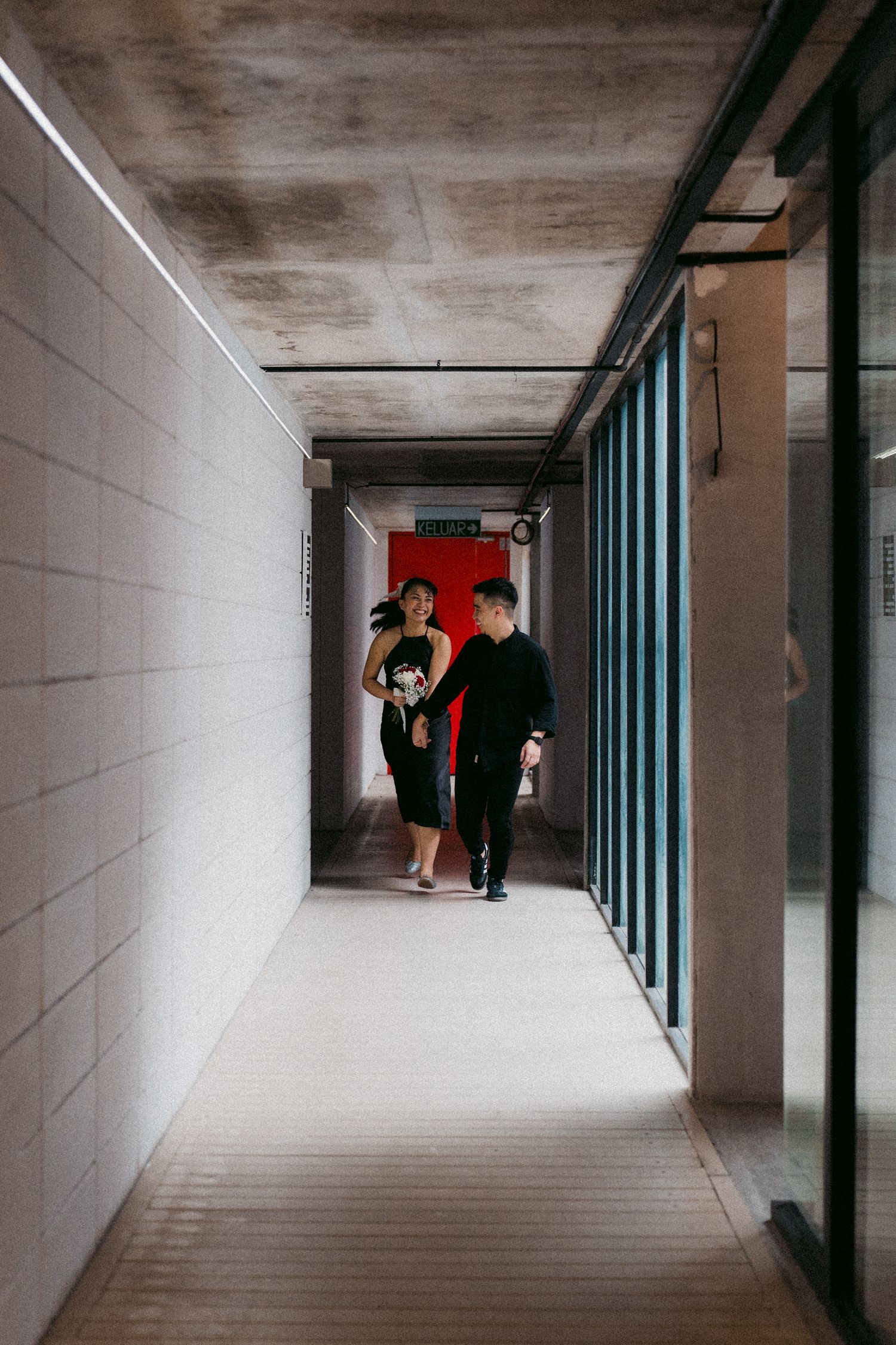 Modern corridor with white walls and glazed windows where two figures engage in conversation.