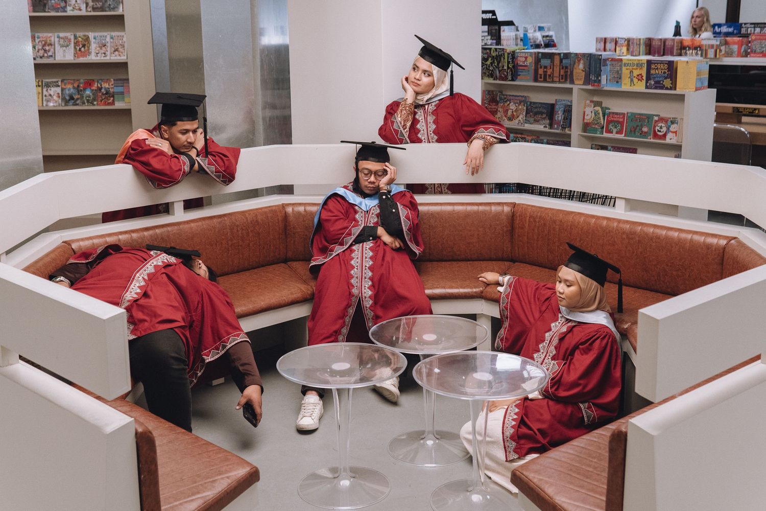 Students in graduation attire socializing in a circular lounge area.