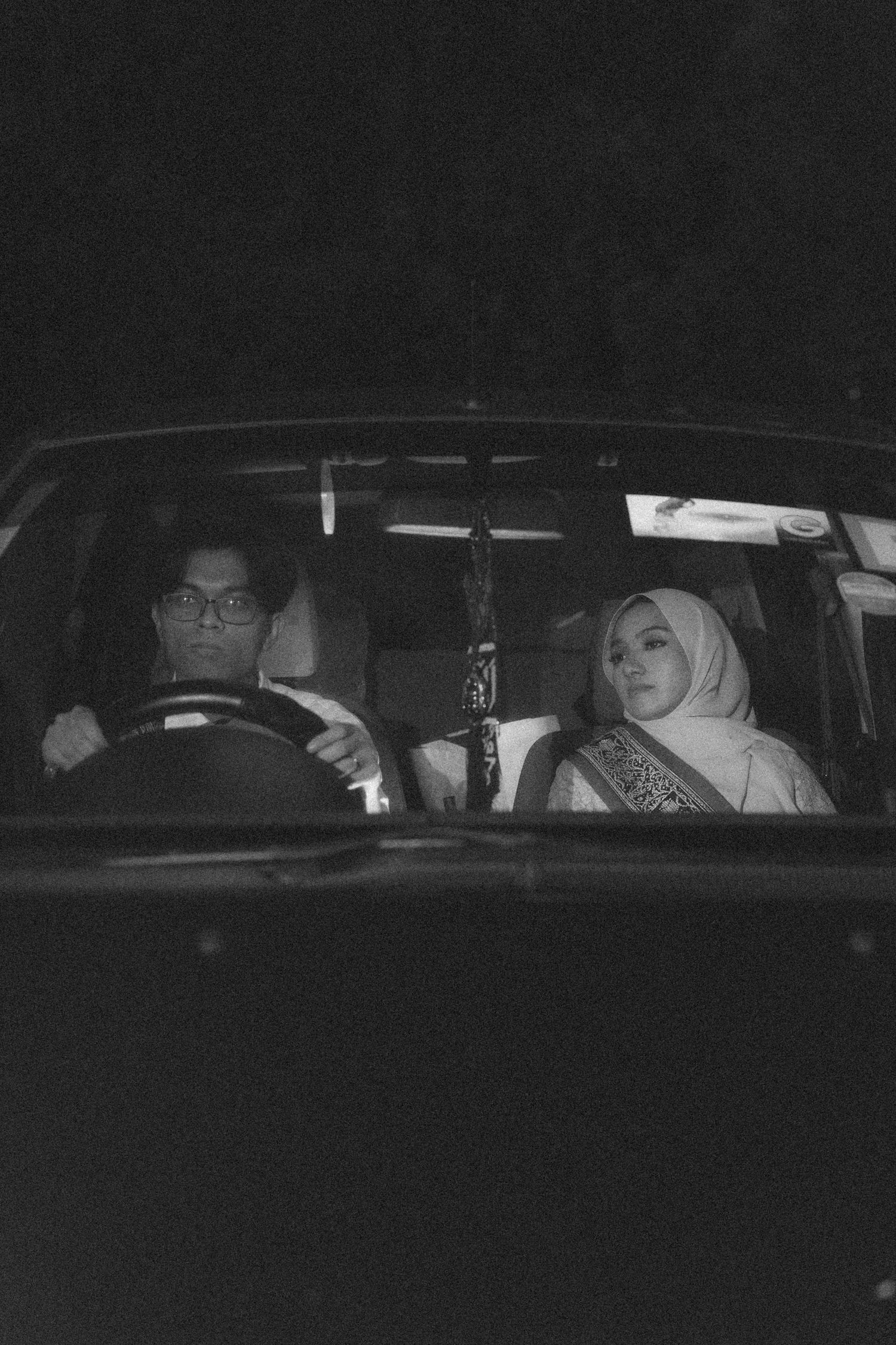 Interior view of two people sitting in car at night.