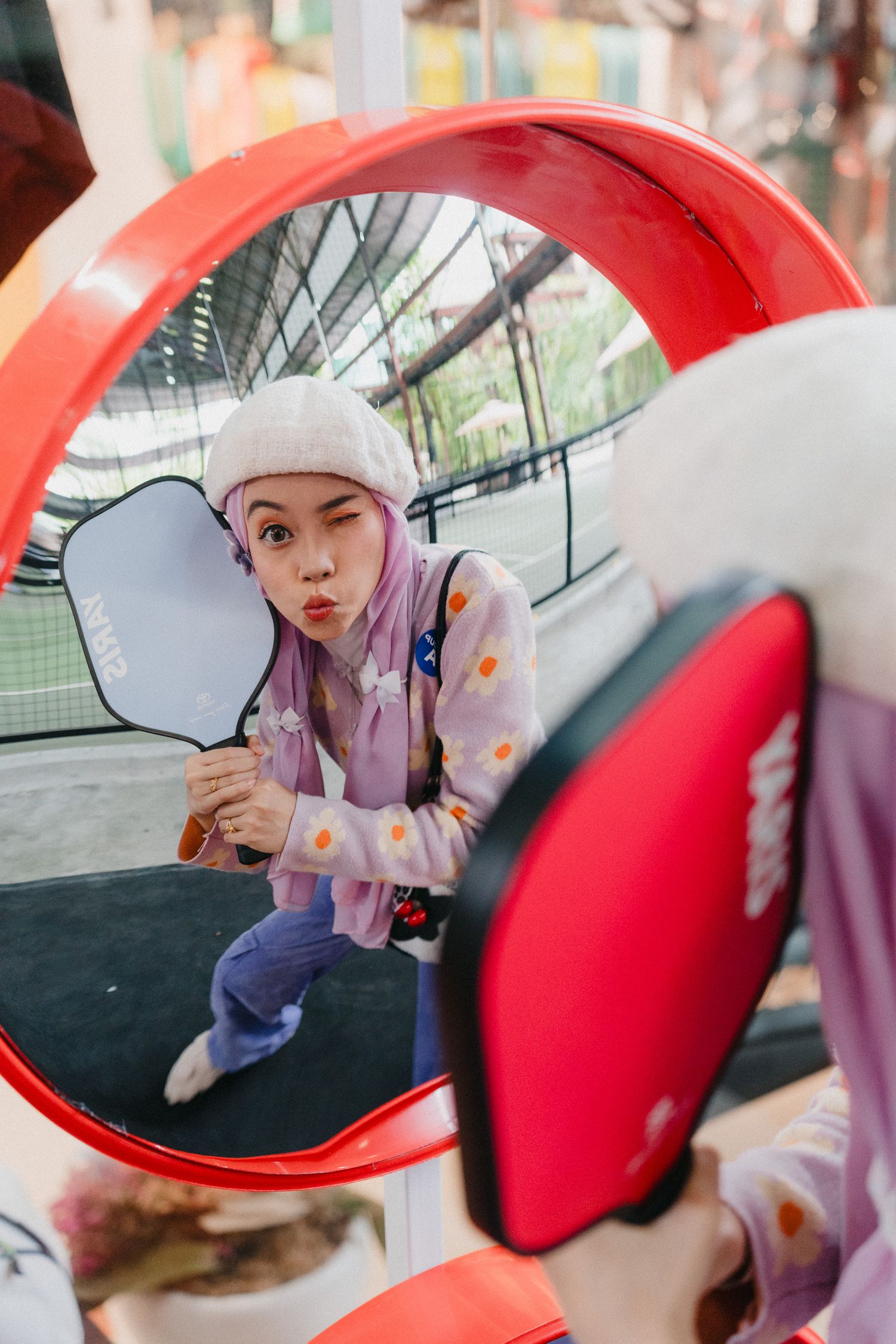 A series of artistic photos showing someone in a lavender outfit and white hat reflected in red side-view car mirrors.