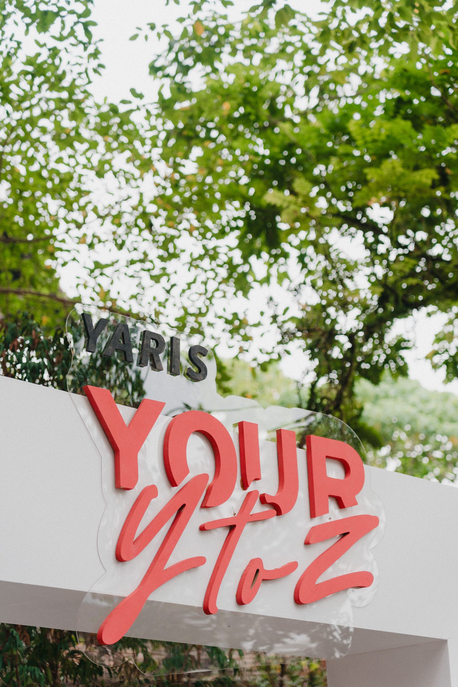Red letters spelling 'YOUR' mounted on a white wall structure with green trees visible in the background.