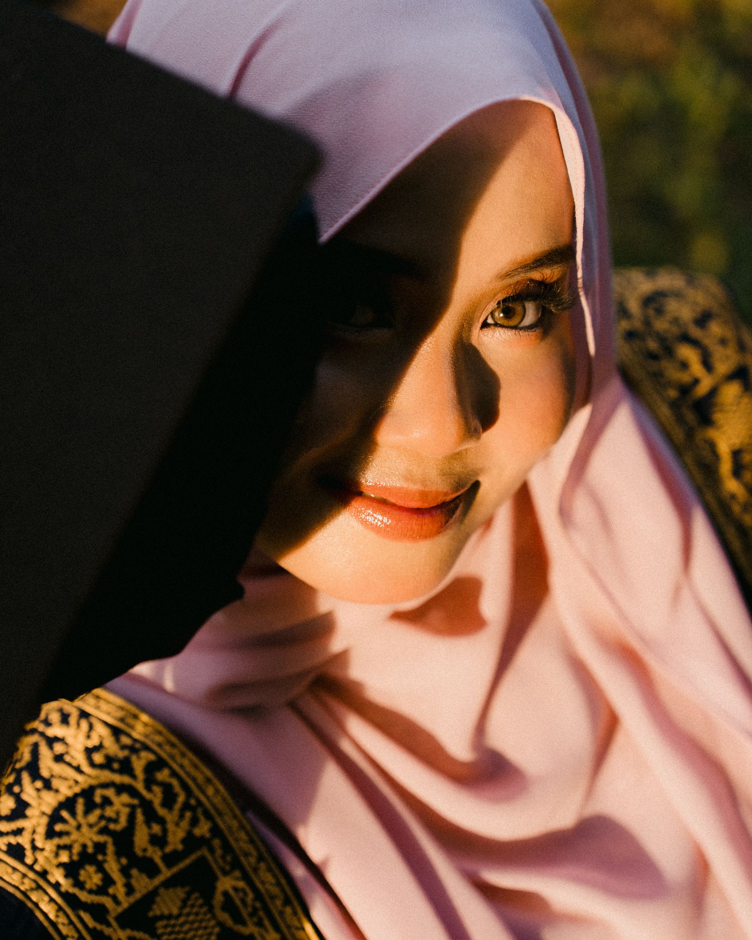 A series of artistic portraits showing a person in a light pink hijab with dramatic lighting and shadows against a dark background.