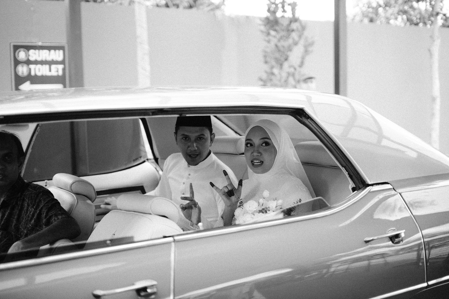 A black and white photograph of two passengers sitting in a classic car.