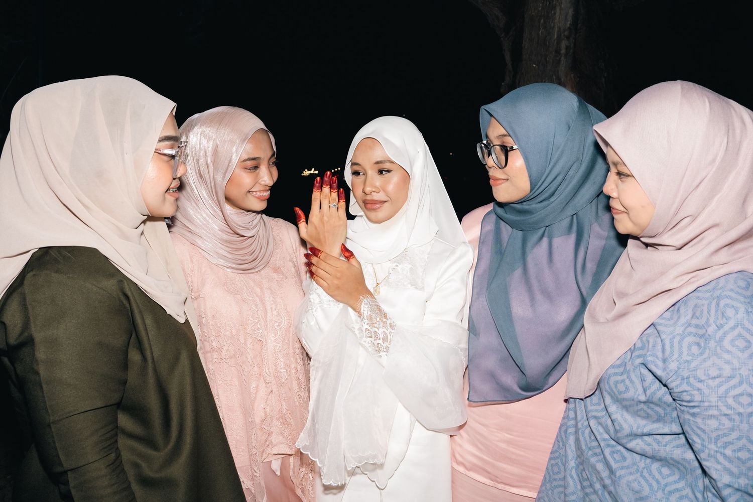 Five friends wearing hijabs in earth tones and pastel colors share a close conversation together.