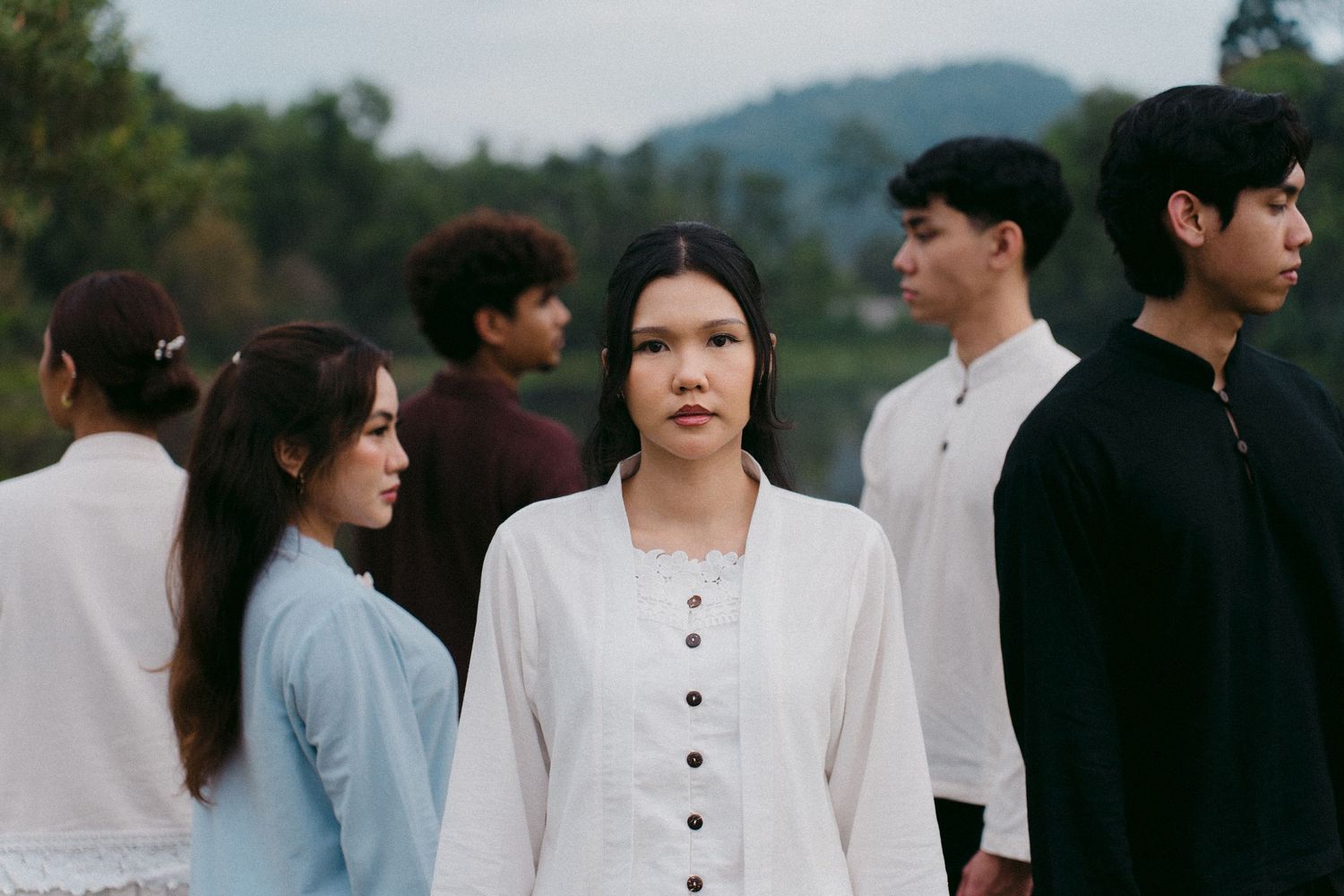 Fashion models in monochromatic outfits posed outdoors with mountains in background.