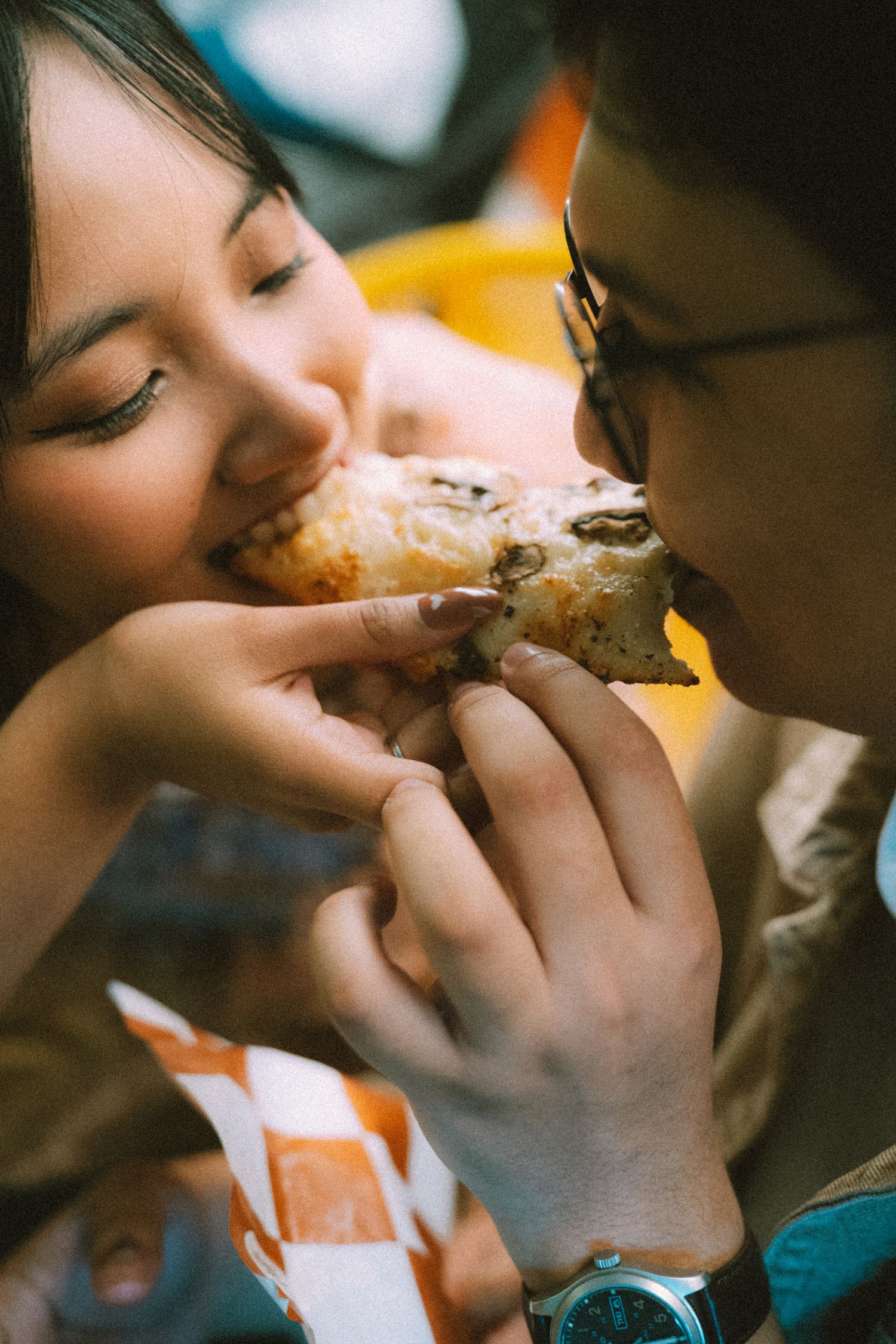 A romantic moment sharing a slice of pizza in warm intimate lighting.