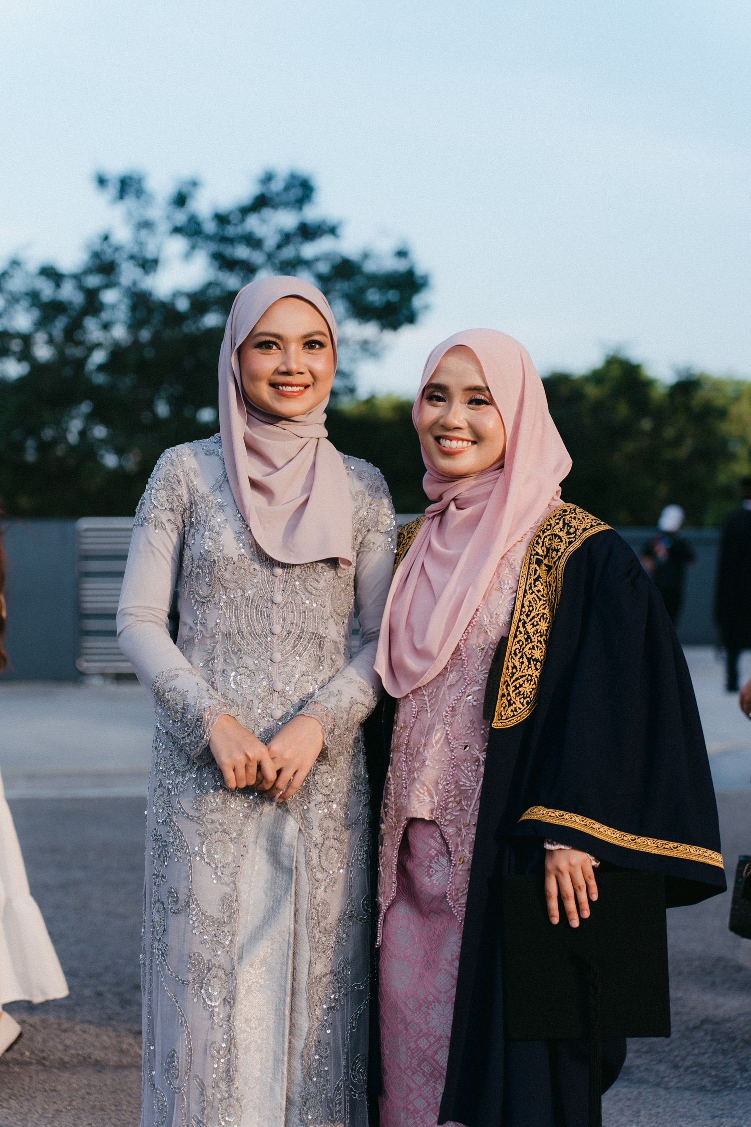 Two people wearing hijabs and formal attire pose together outdoors at dusk in a series of candid shots.