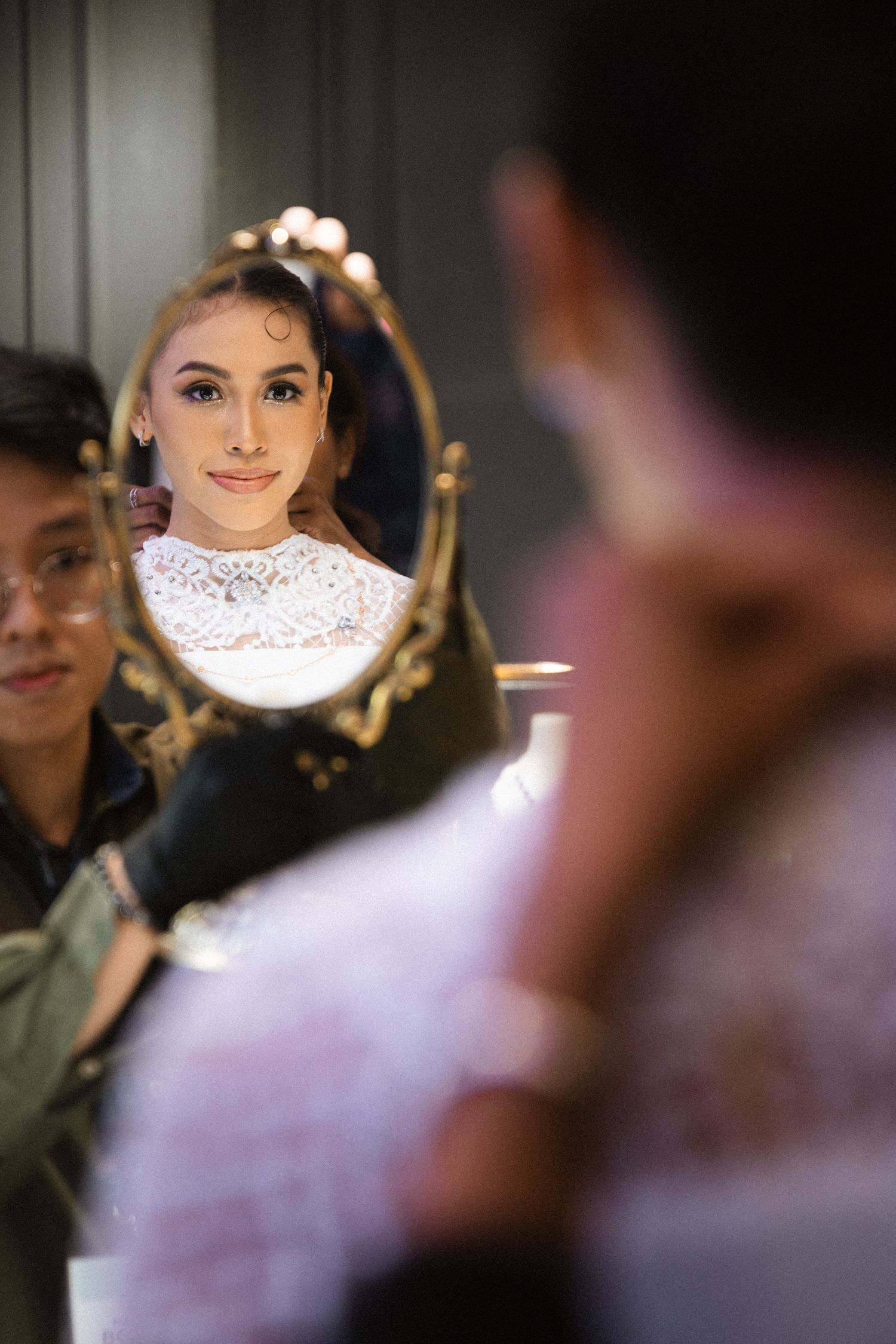 Reflection in ornate gold mirror during bridal preparation.